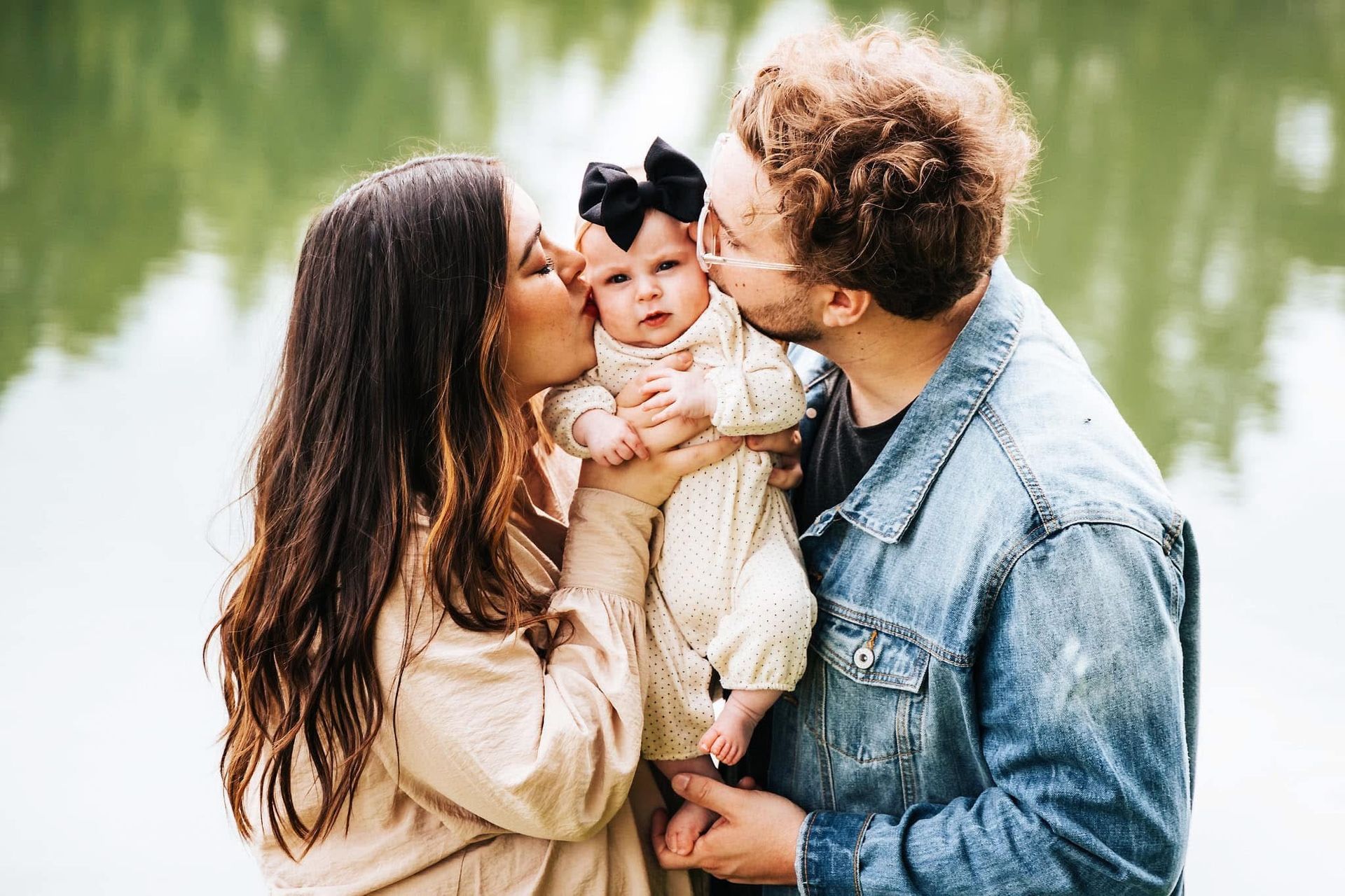 A man and woman are kissing a baby on the cheek.