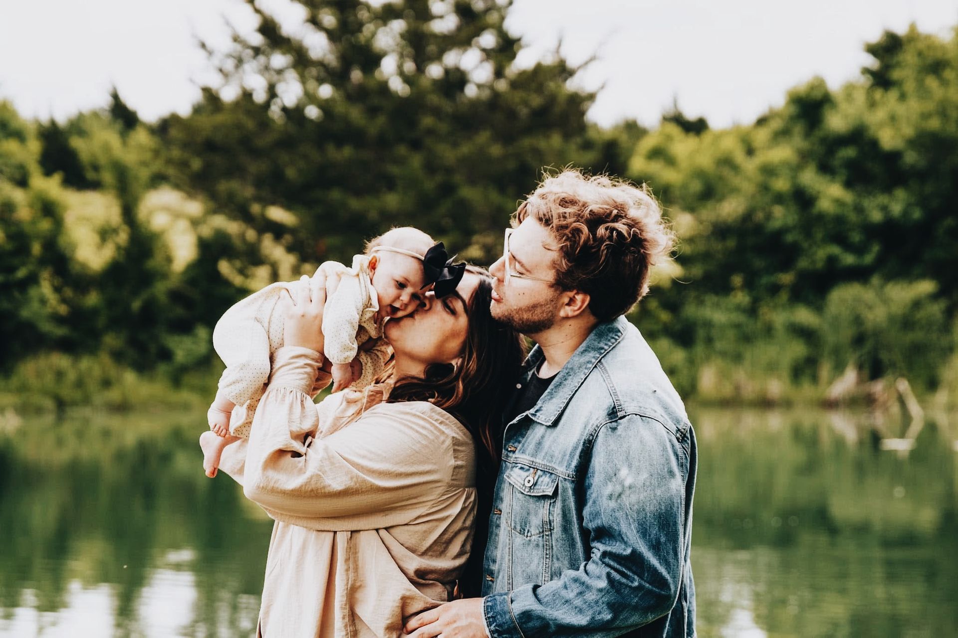a young family engages playfully on a riverbank