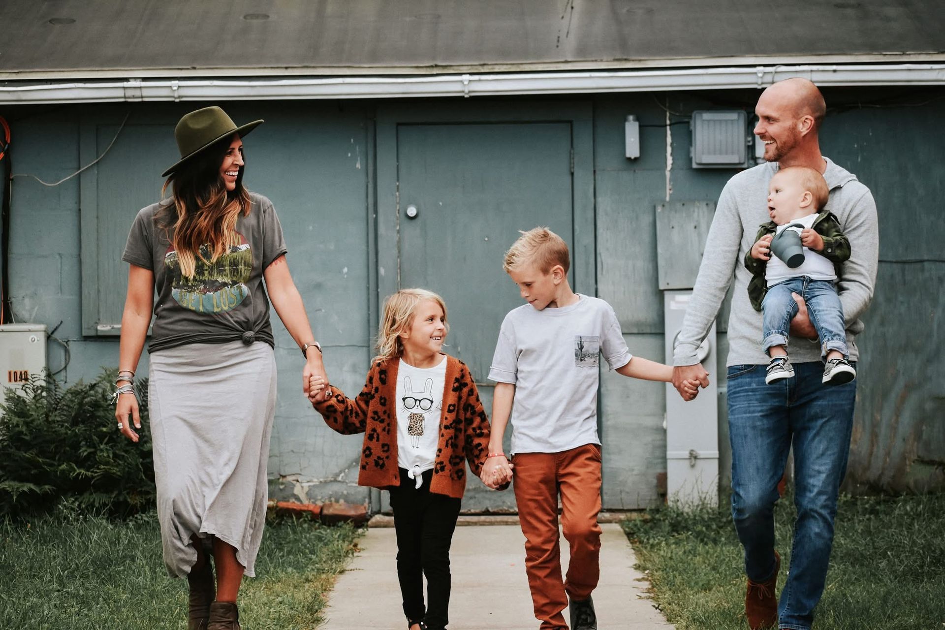 A family is walking down a sidewalk holding hands.