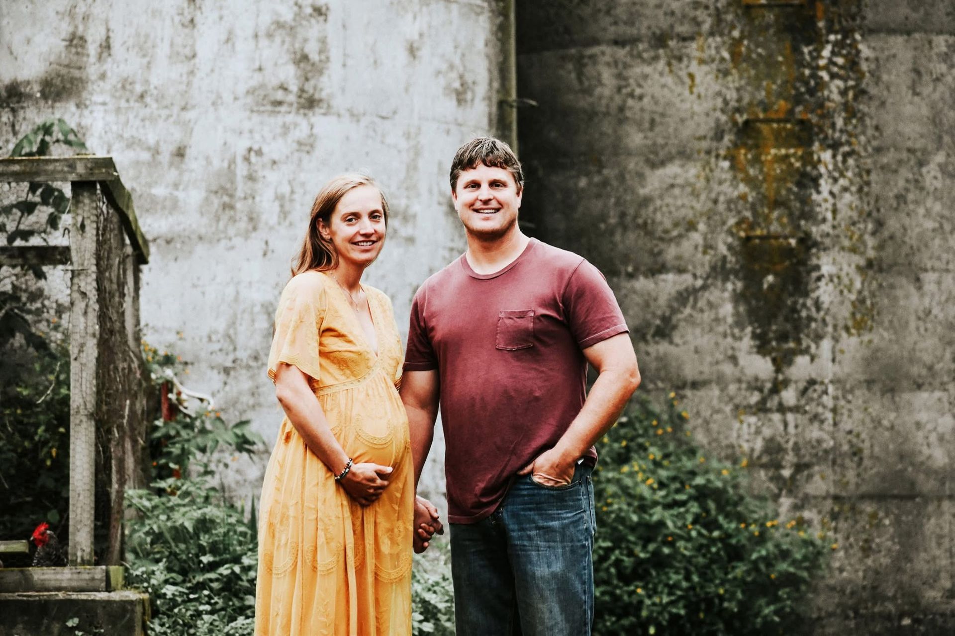 A man and a pregnant woman are standing next to each other holding hands.
