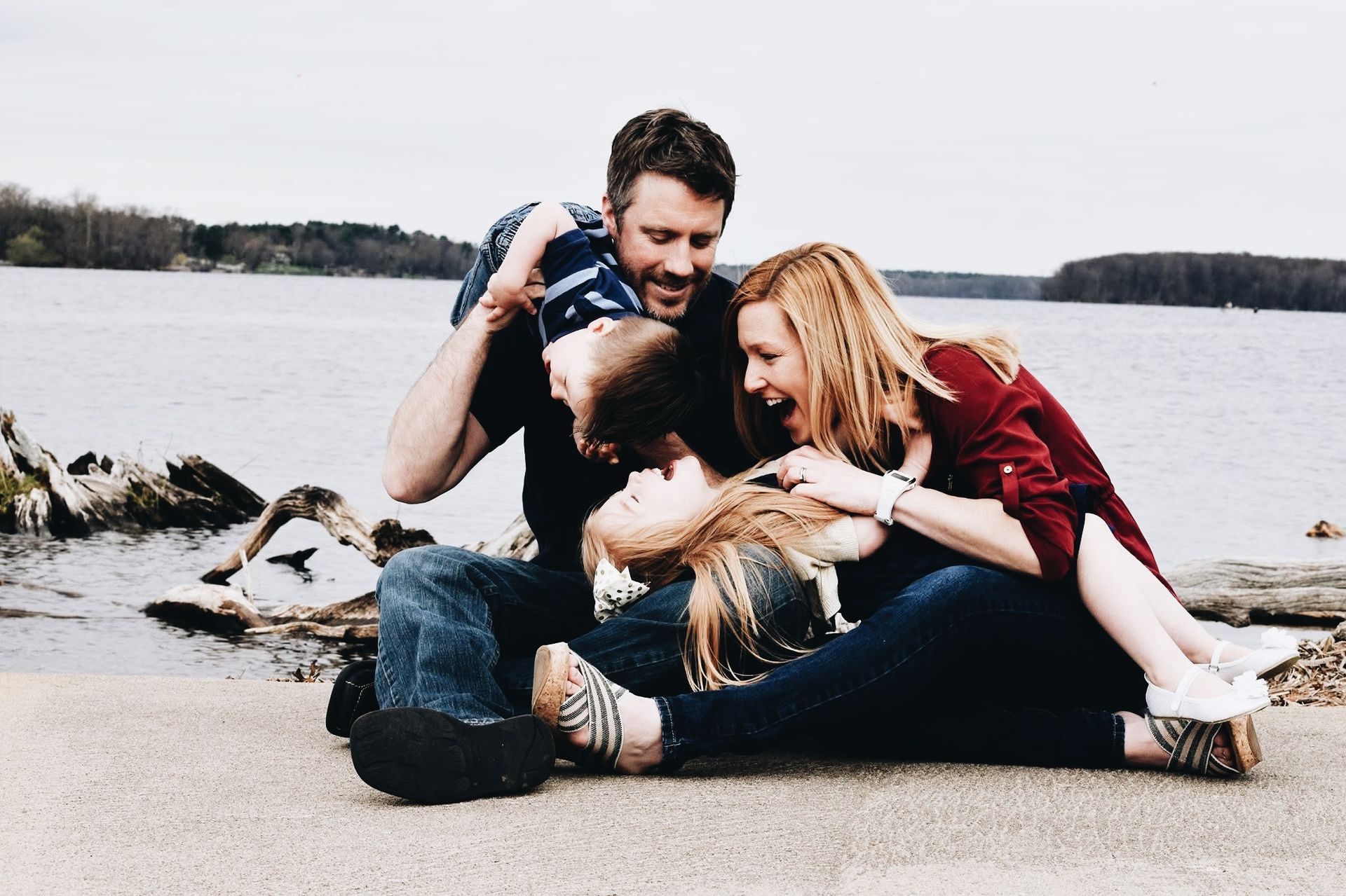 A family is sitting on the ground near a lake.