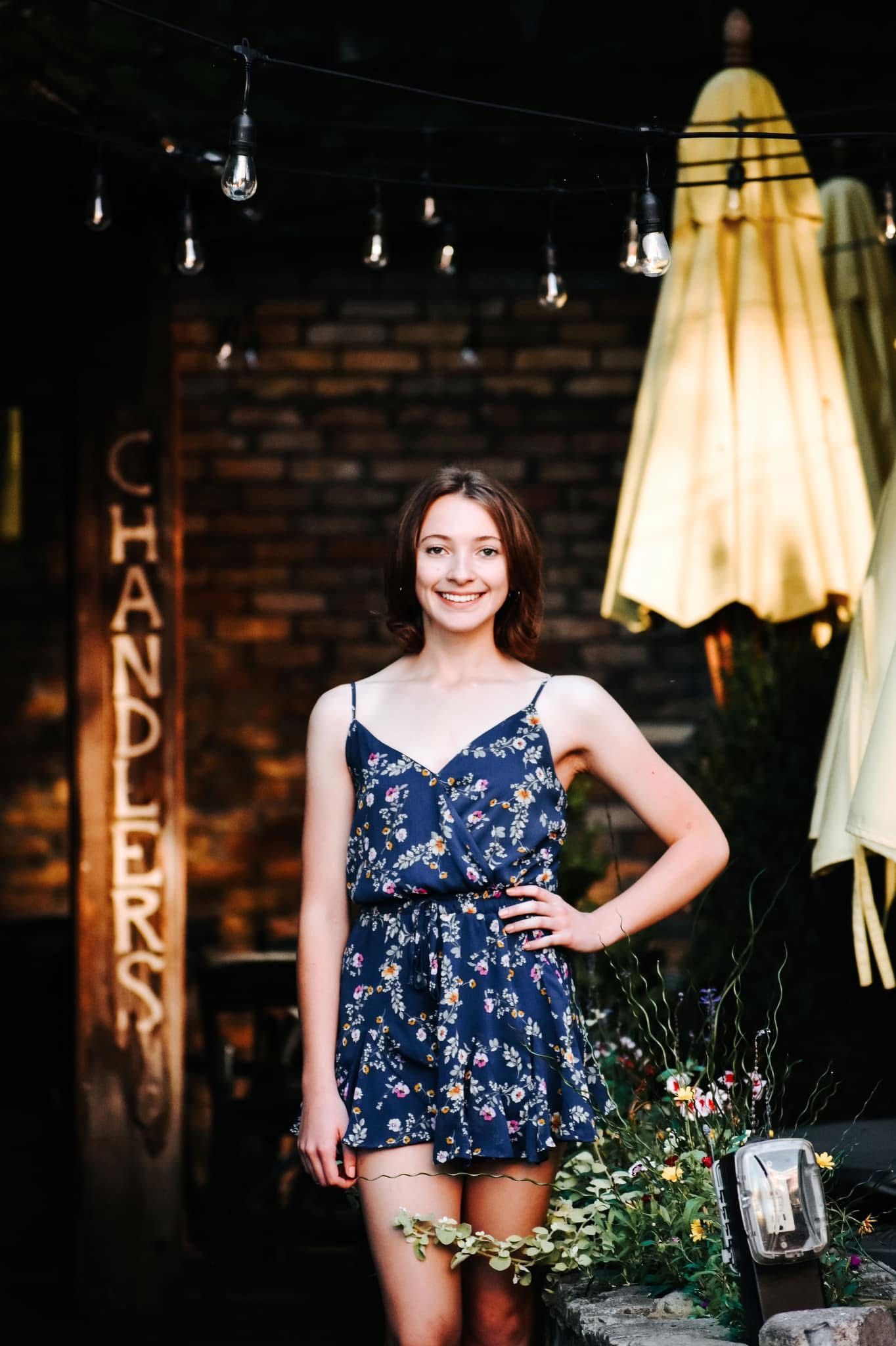 A woman in a blue dress is standing in front of a sign that says chandler.