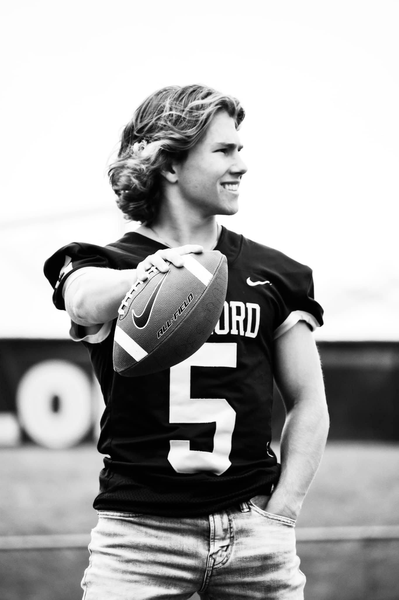 A young man in a jrd jersey is holding a football.