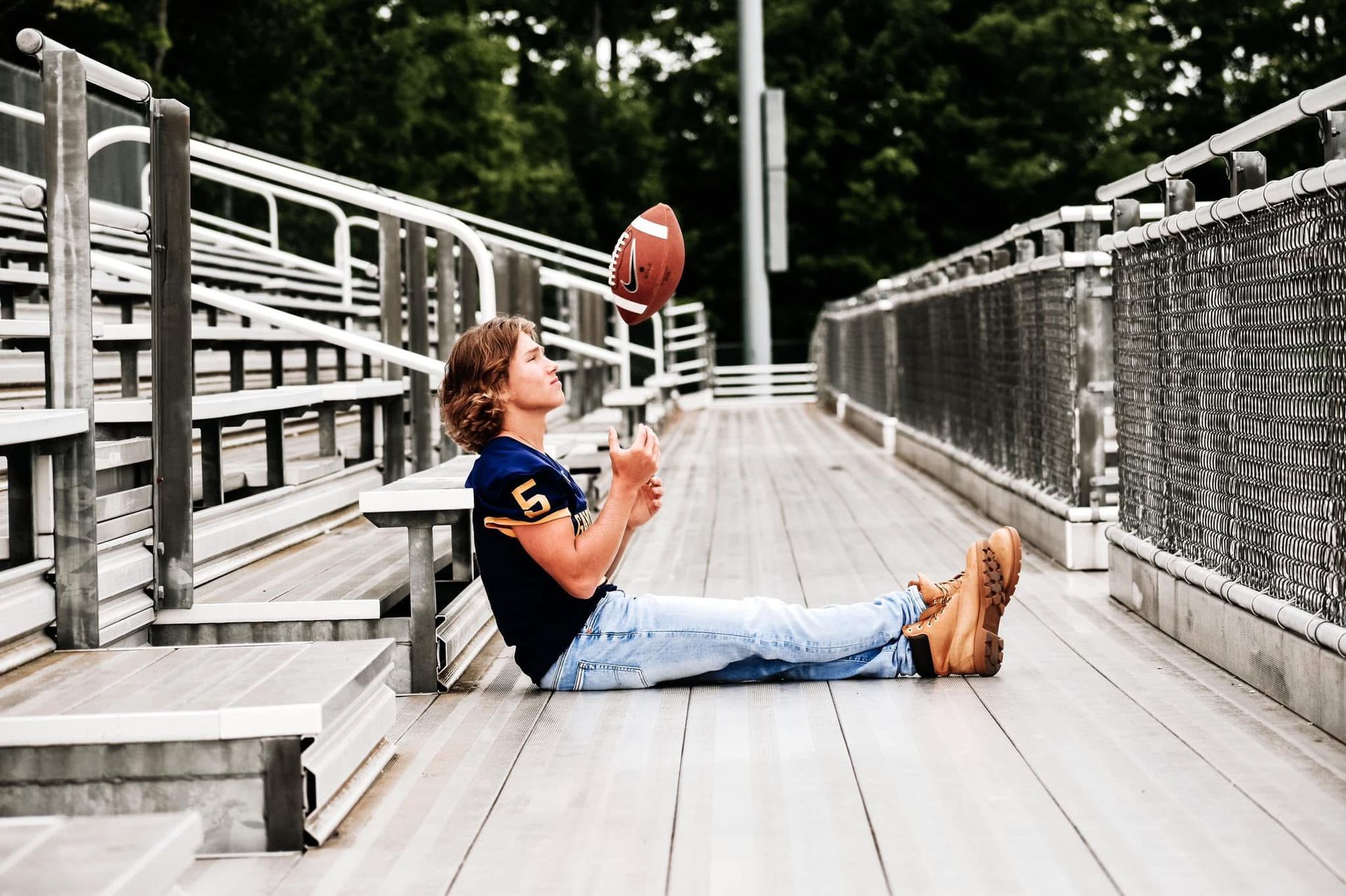 A young boy is sitting on the ground holding a football.