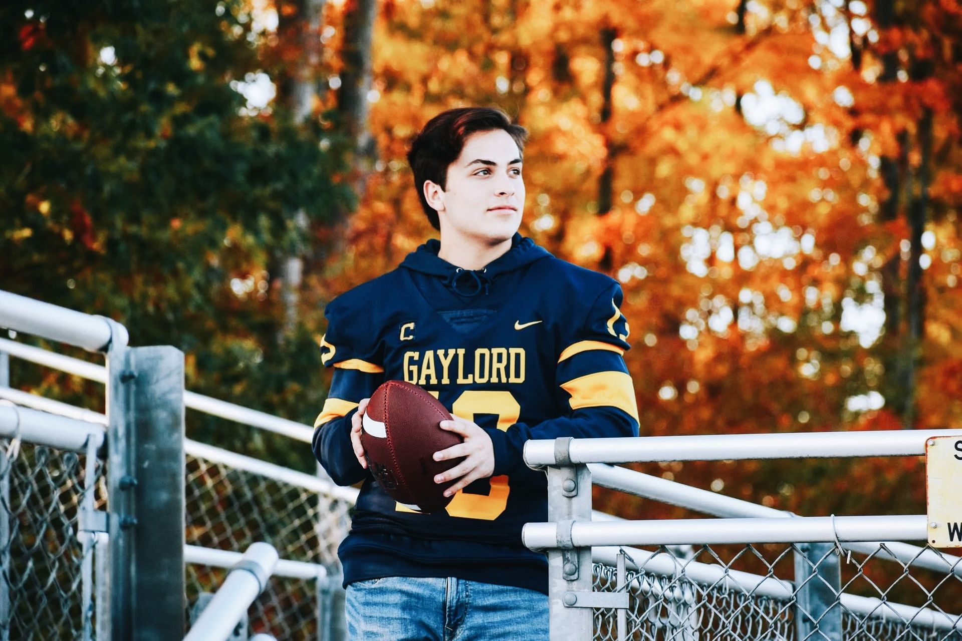 A young man in a gaylord football jersey is holding a football.