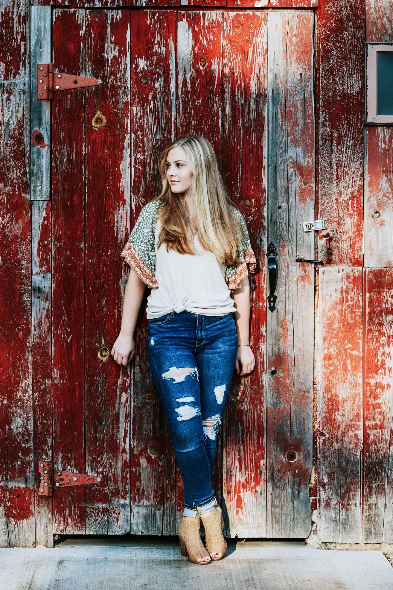 A woman is standing in front of a red door.