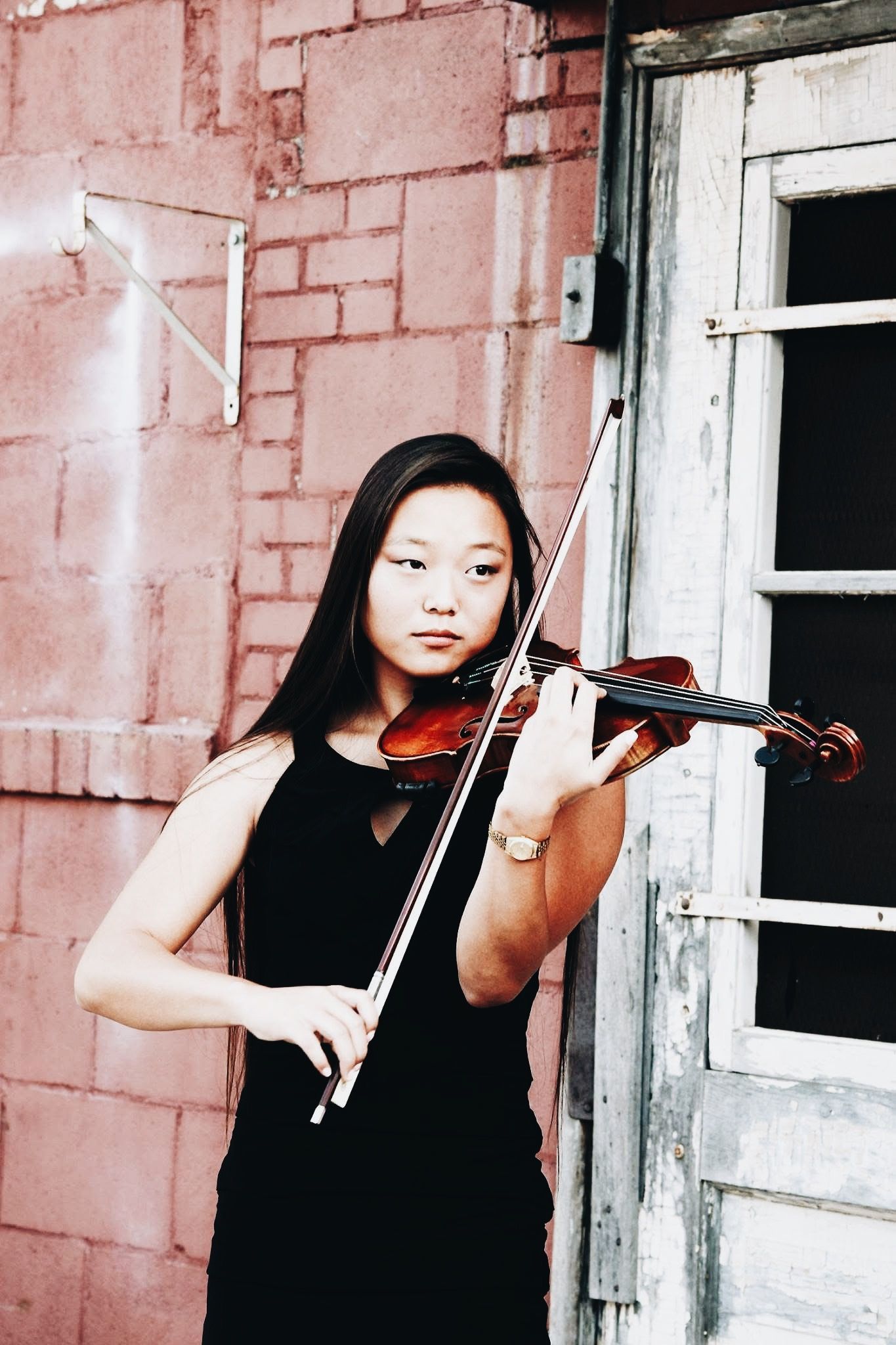 A woman in a black dress is playing a violin
