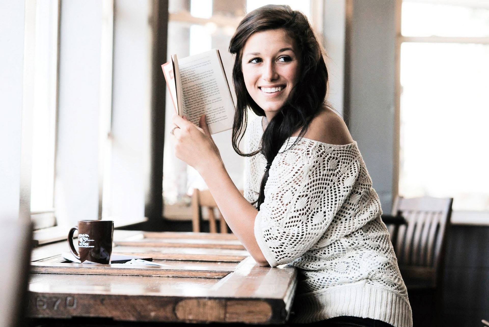 A woman is sitting at a table reading a book.