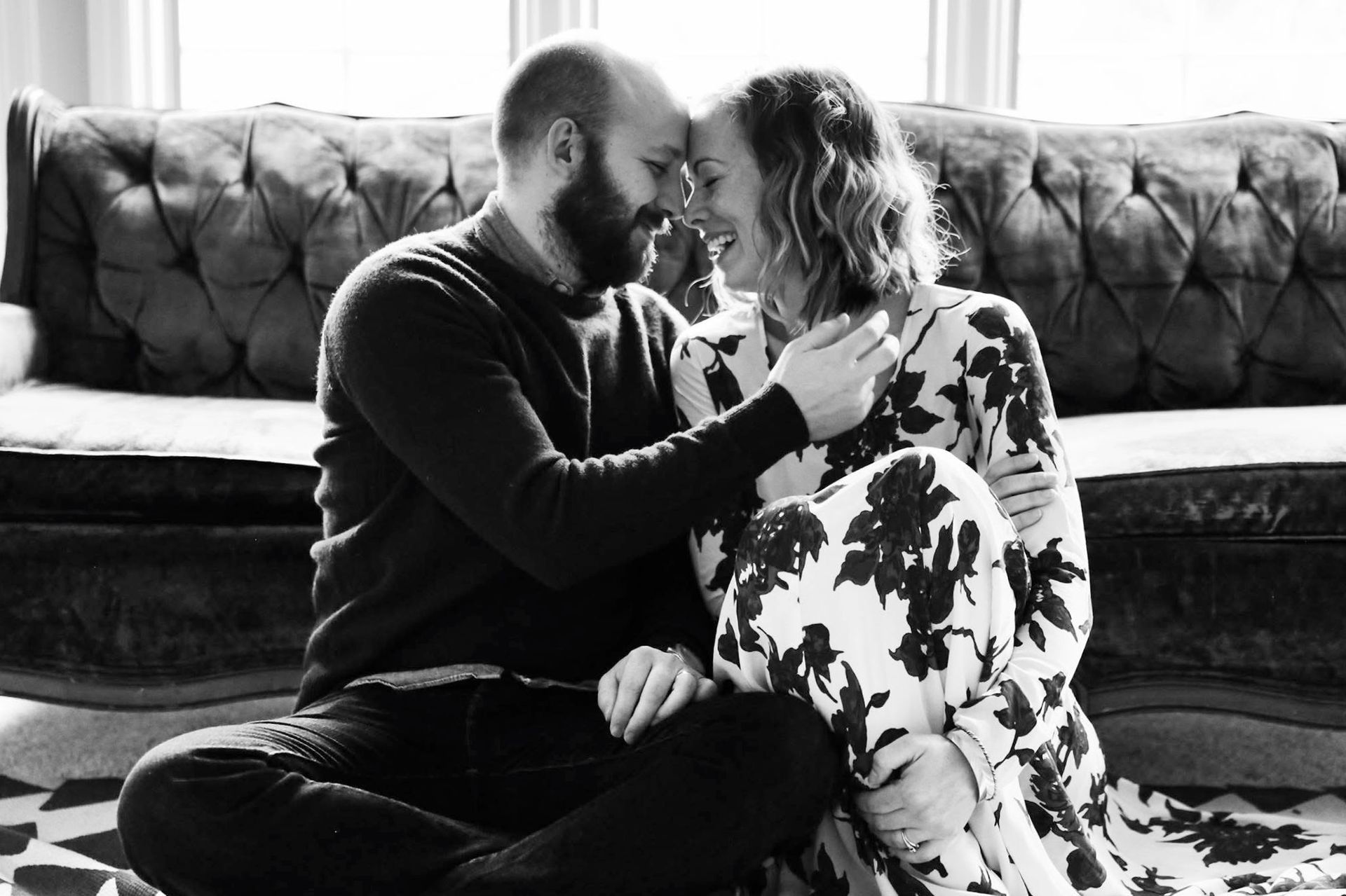 A man and a woman are sitting on the floor in front of a couch.