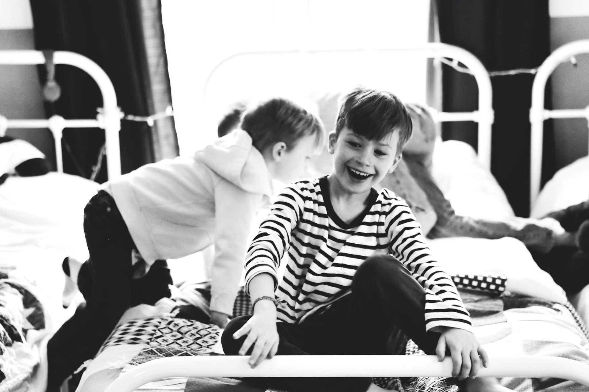 A group of young boys are playing on a bed in a black and white photo.