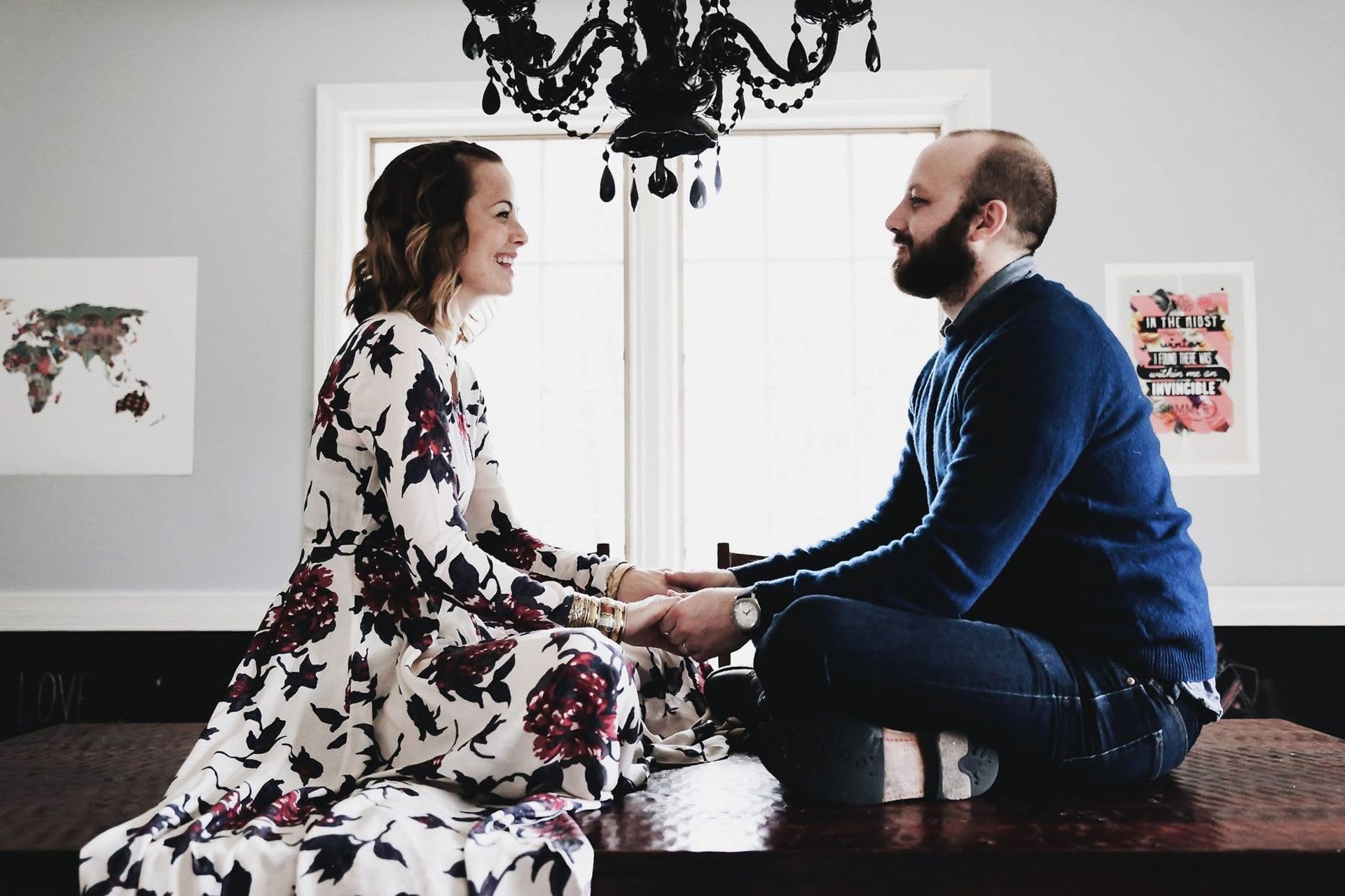 A man and a woman are sitting at a table holding hands.