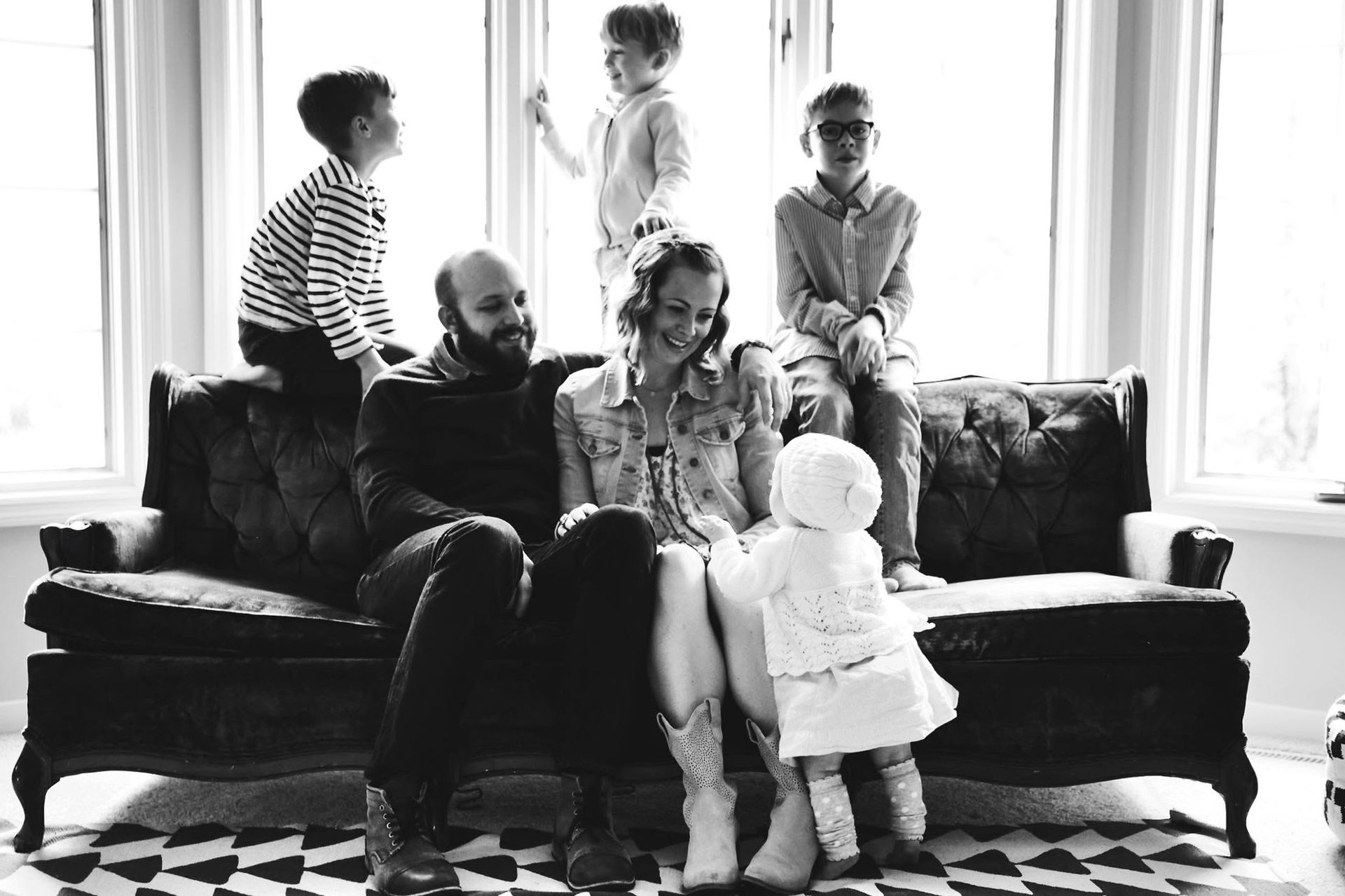 A black and white photo of a family sitting on a couch.