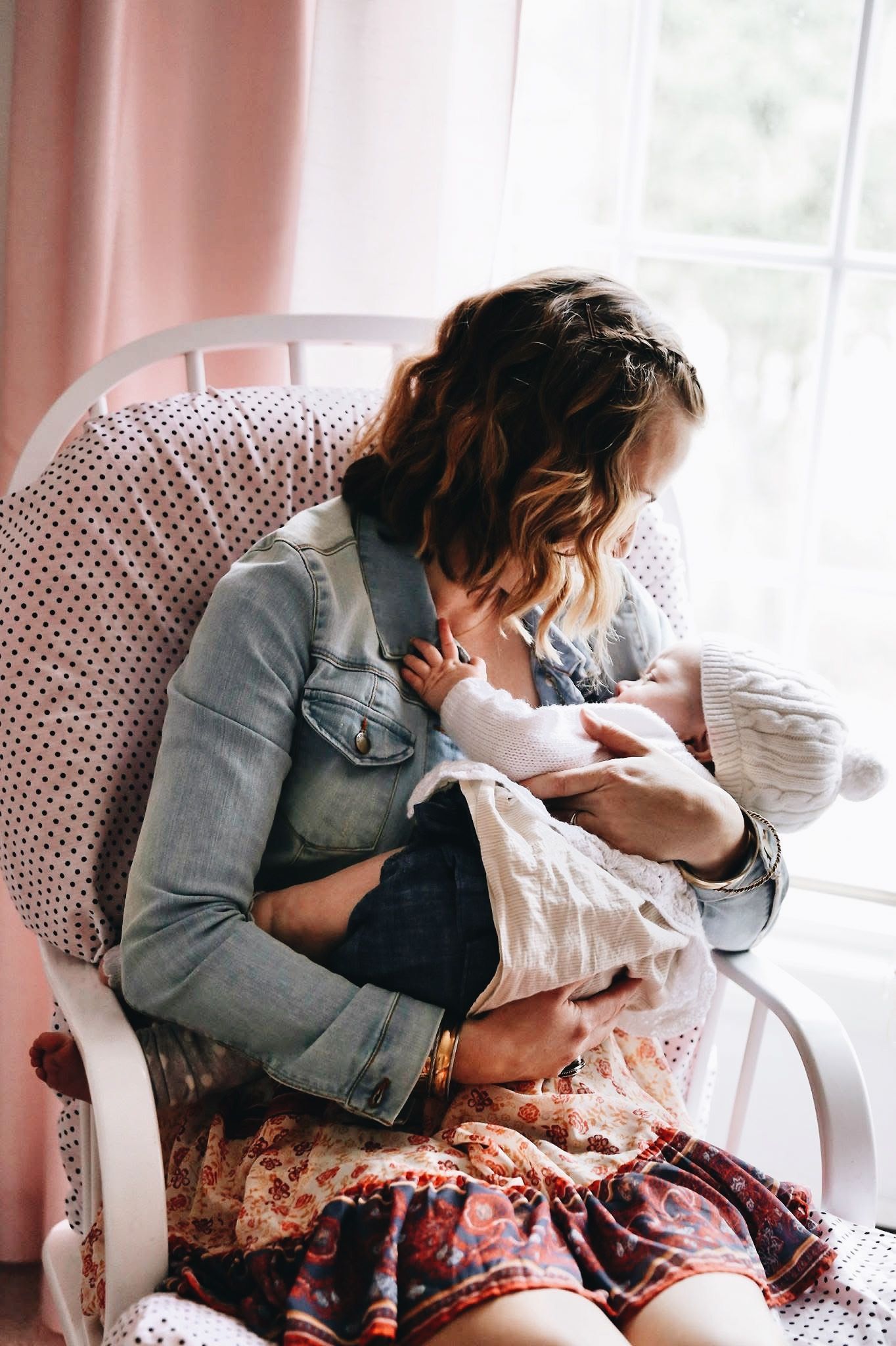 A woman is sitting in a rocking chair holding a baby.