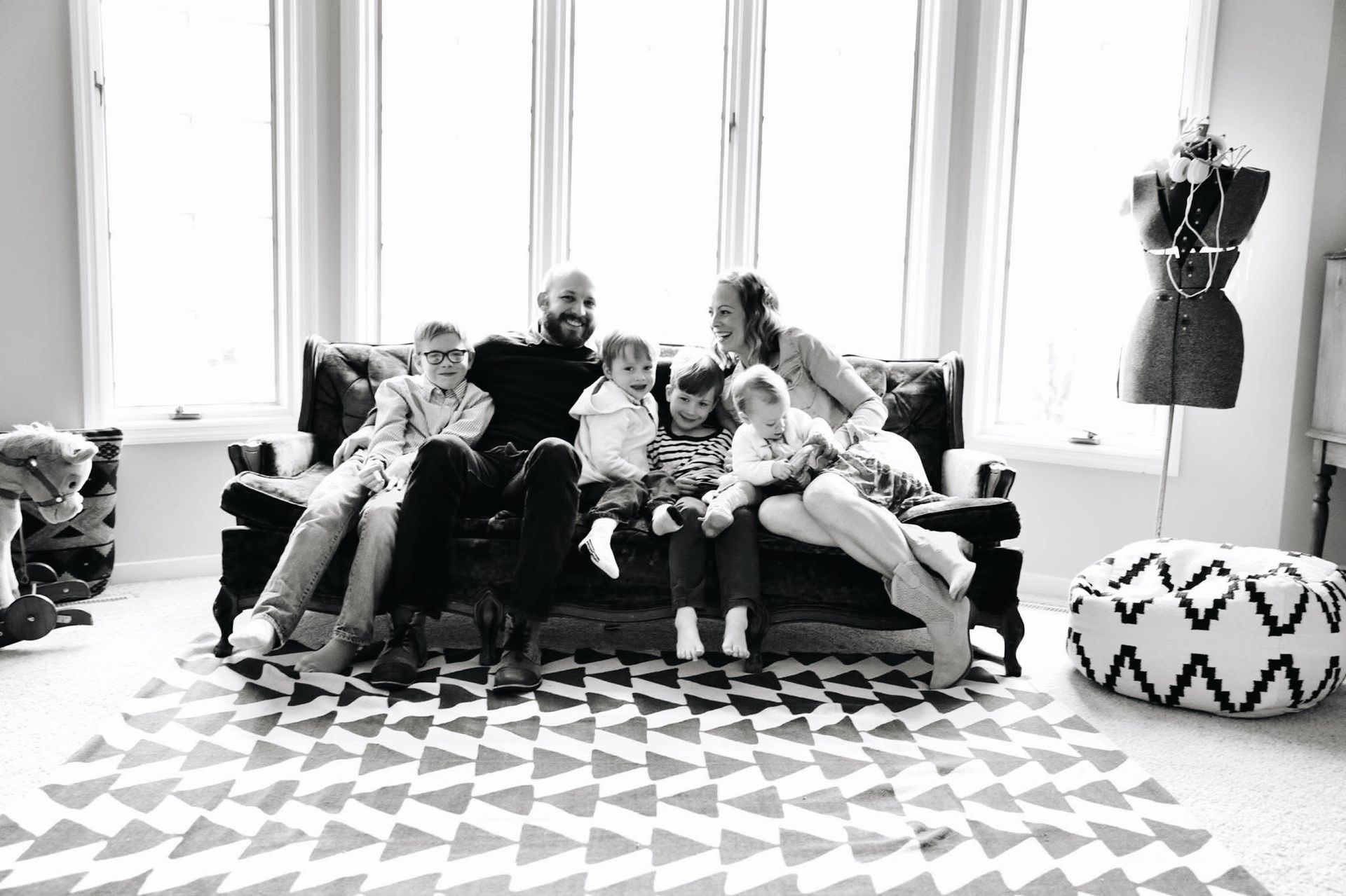 A black and white photo of a family sitting on a couch.