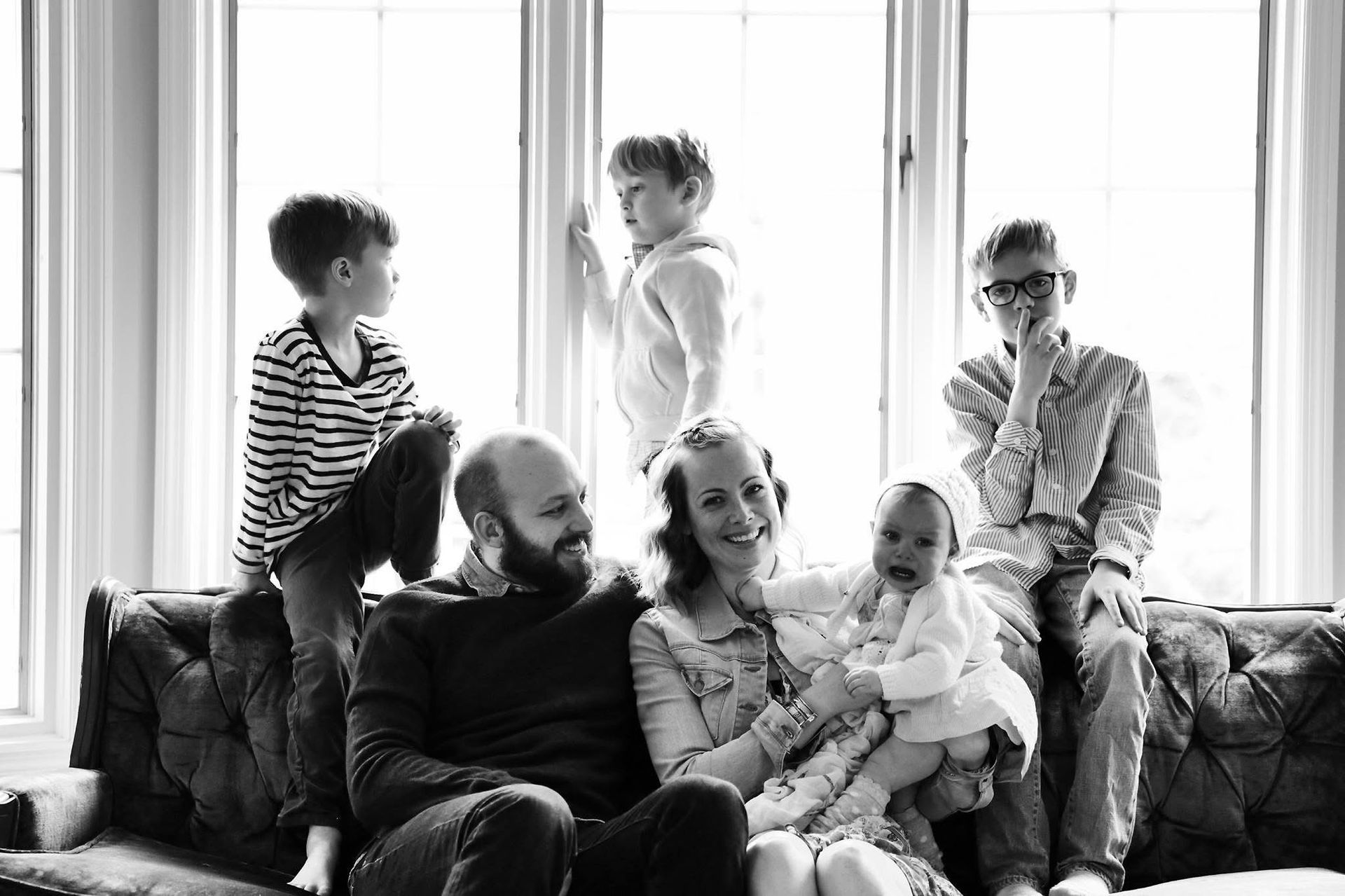 A black and white photo of a family sitting on a couch.