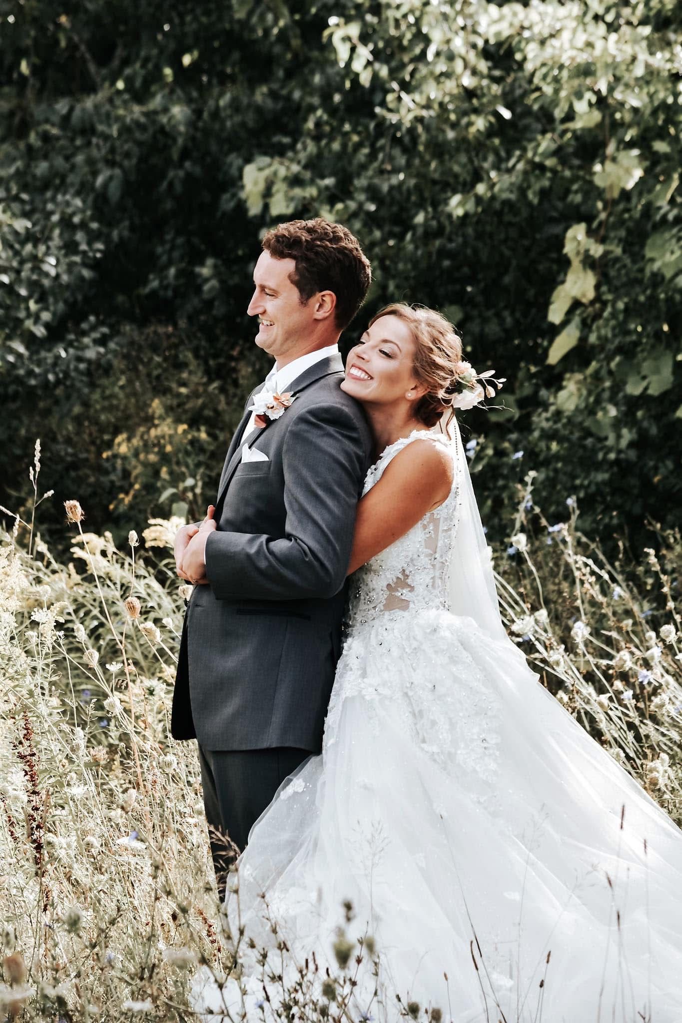 A bride and groom are posing for a picture in a field of flowers.