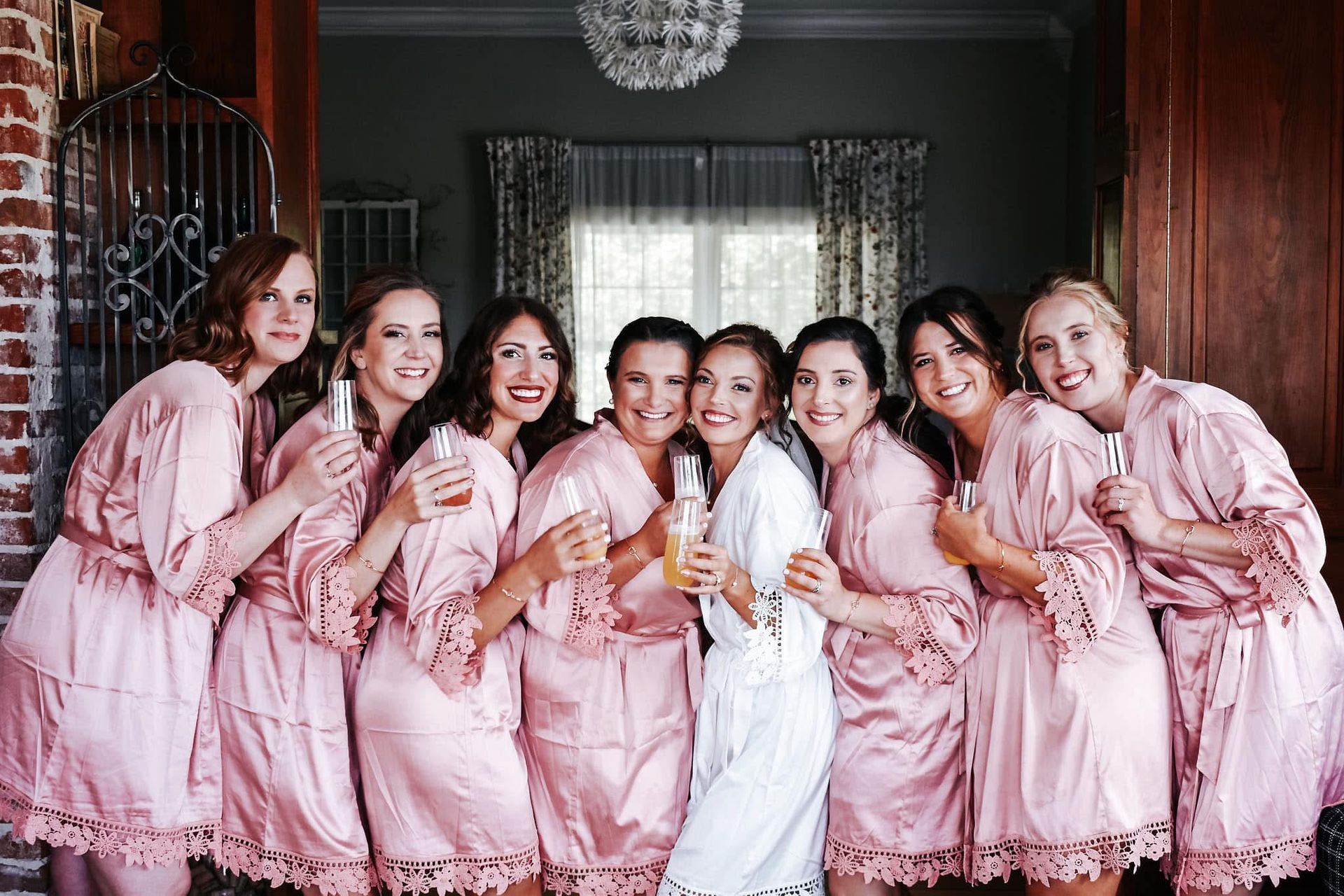 A bride and her bridesmaids are posing for a picture while holding champagne glasses.