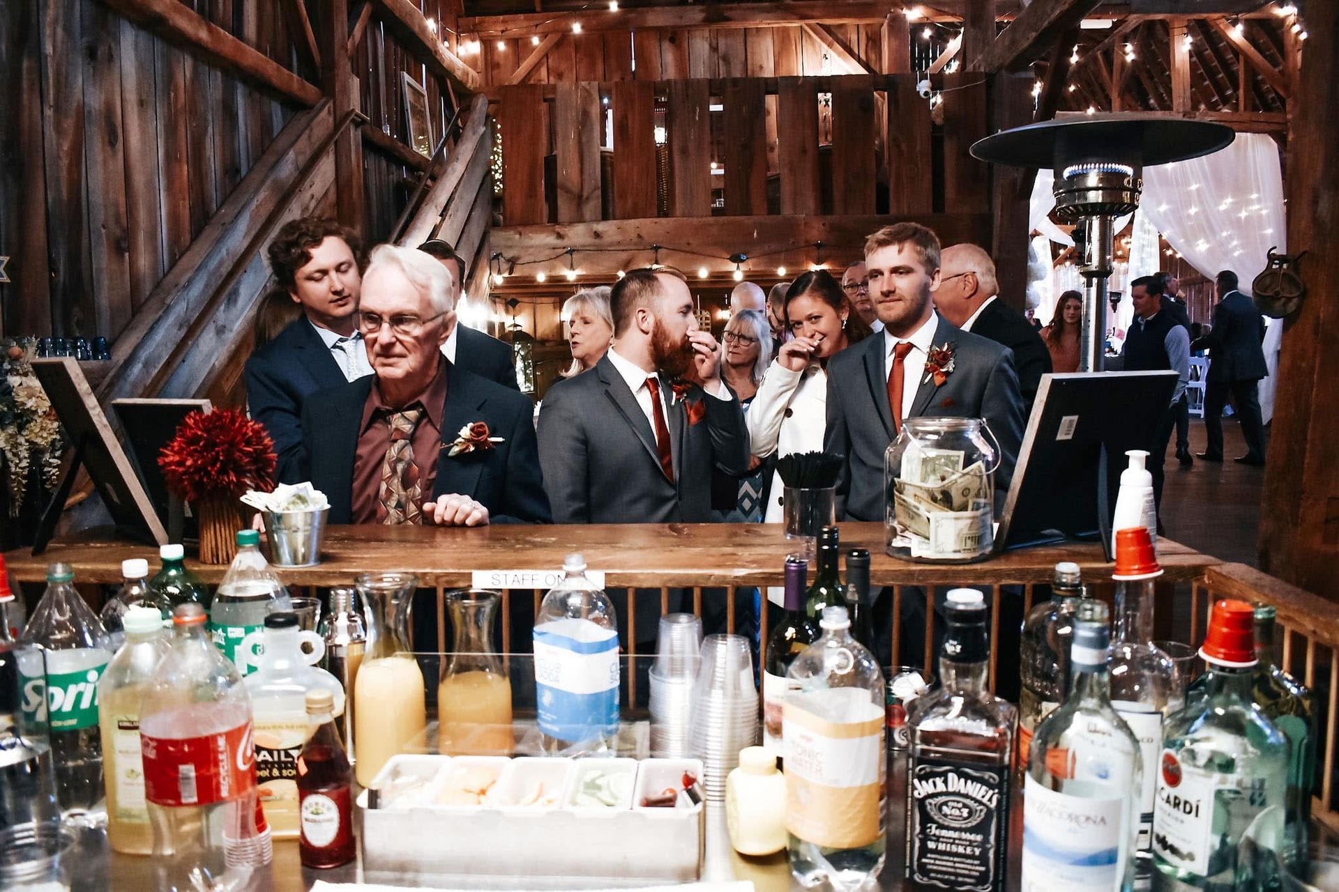 A group of people are standing around a bar filled with bottles of alcohol.