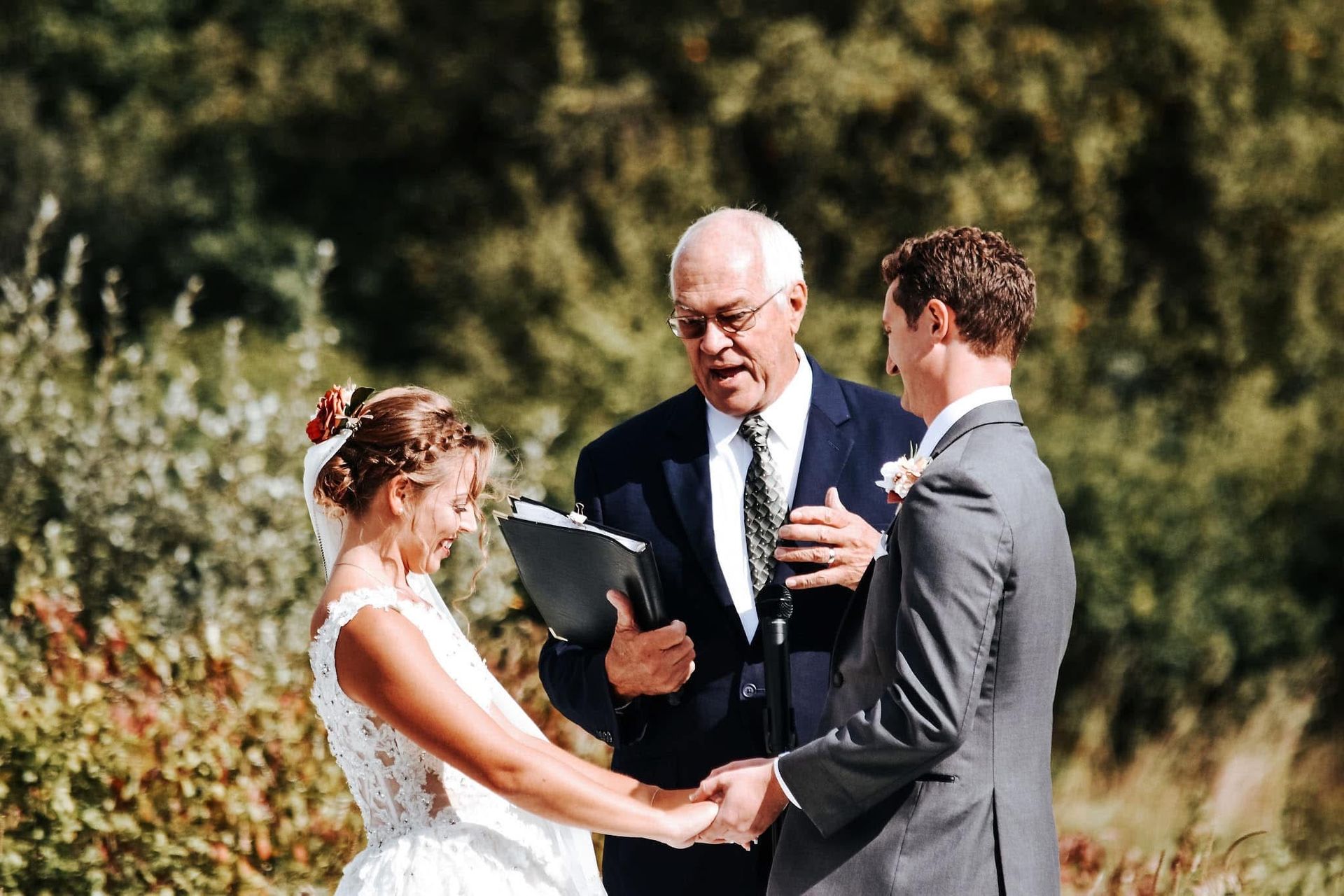 A bride and groom are holding hands during their wedding ceremony.
