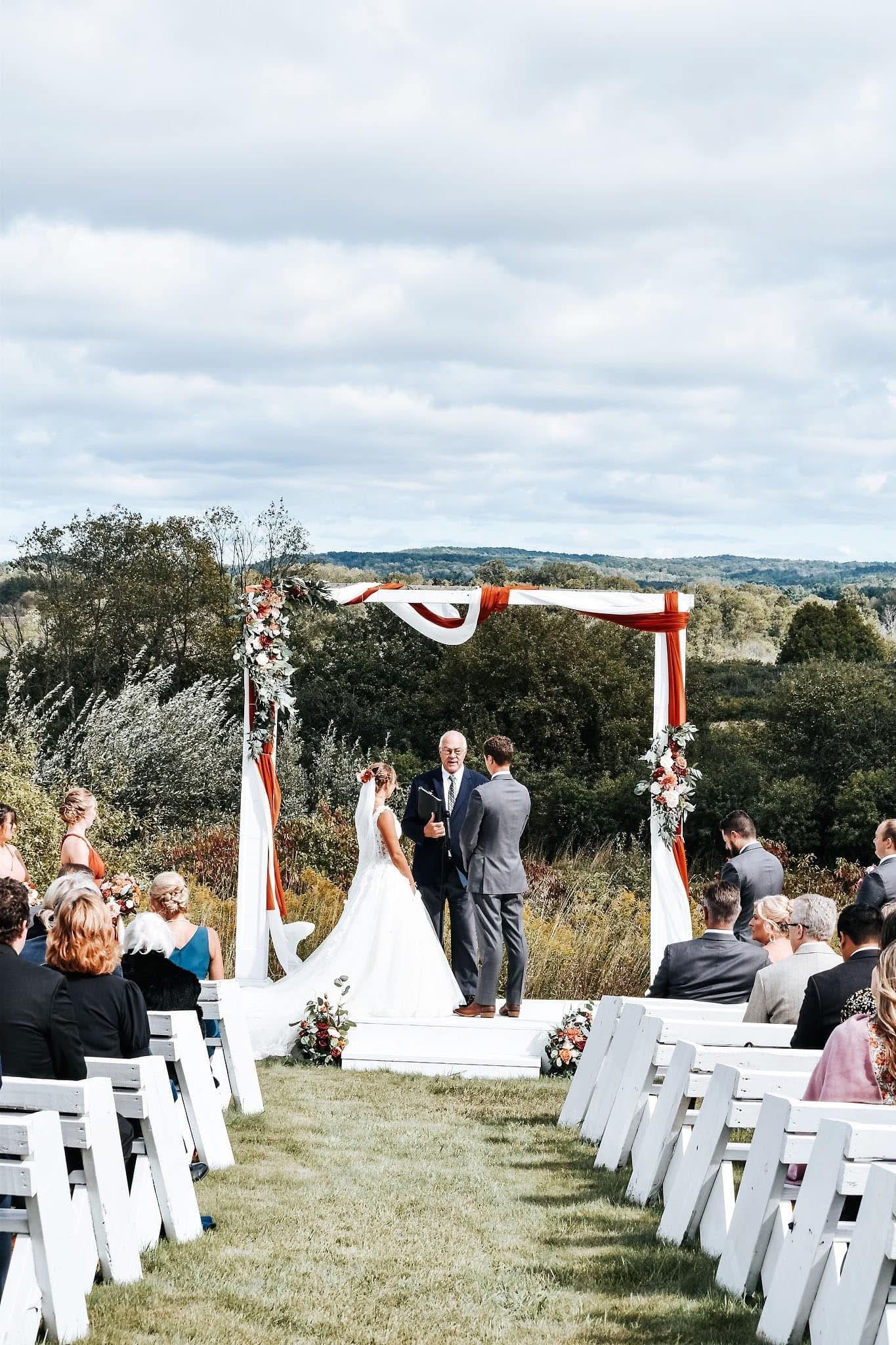 A bride and groom are getting married in front of a crowd of people at a wedding ceremony.