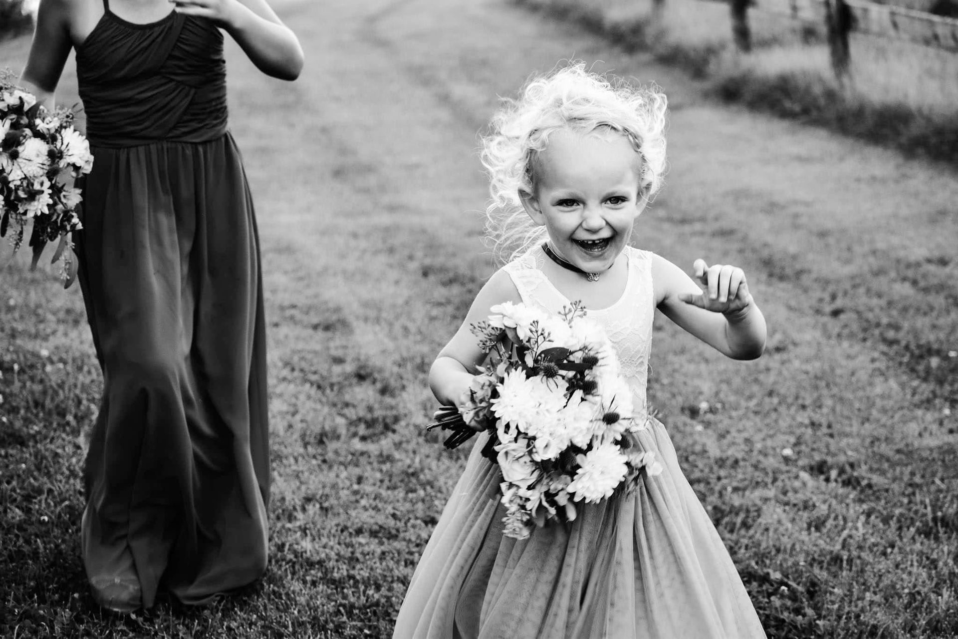 A black and white photo of a flower girl holding a bouquet of flowers.
