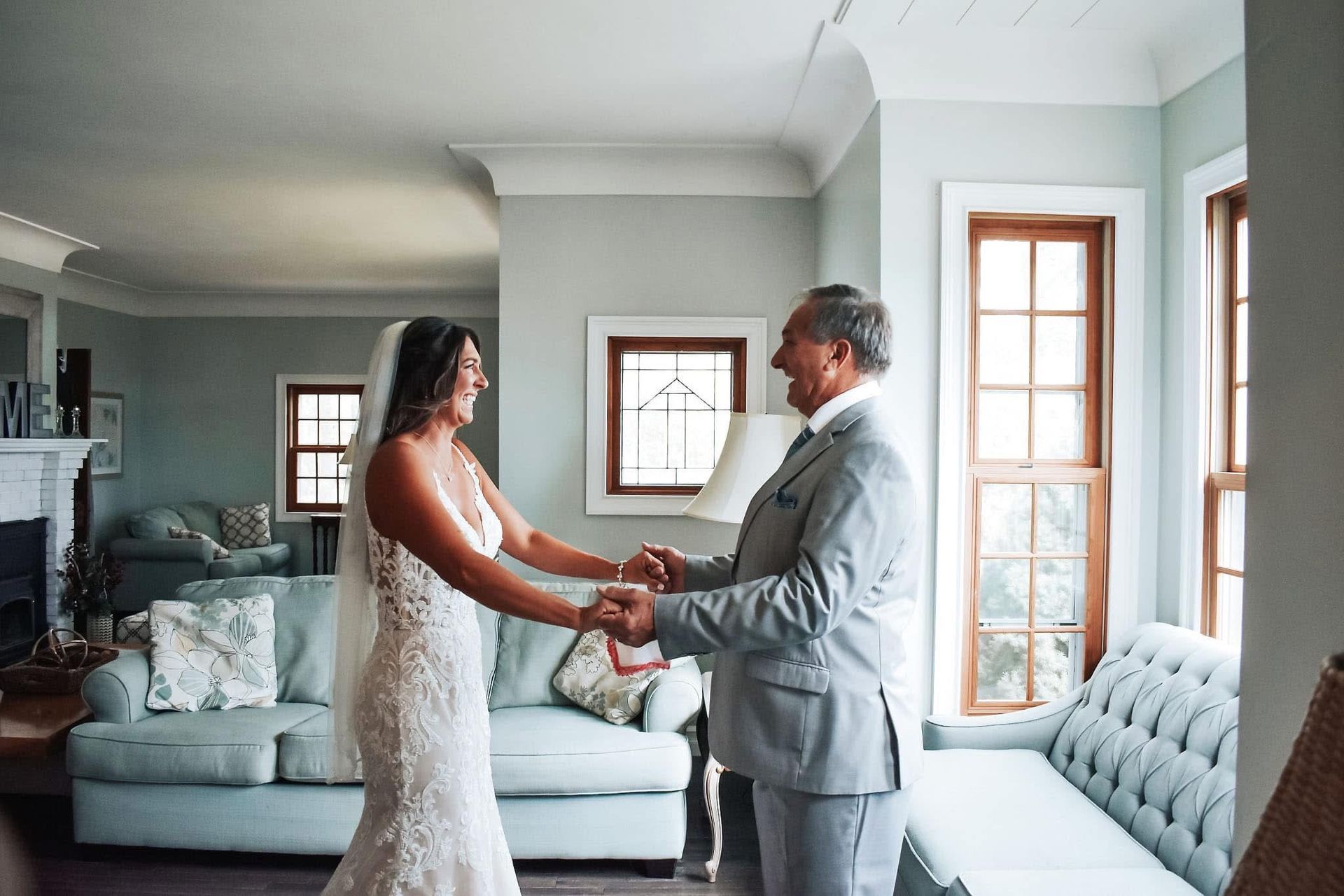A bride and groom are holding hands in a living room.