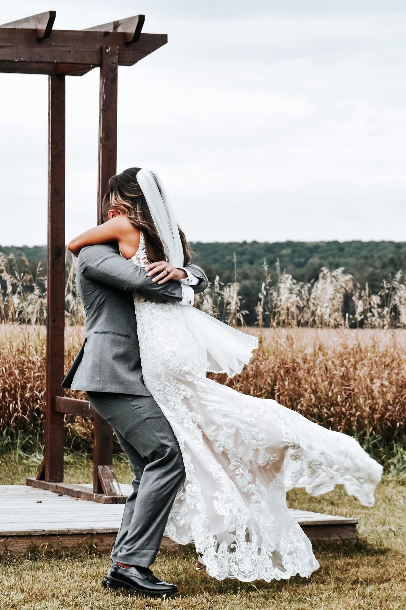 A bride and groom are posing for a picture in a field.