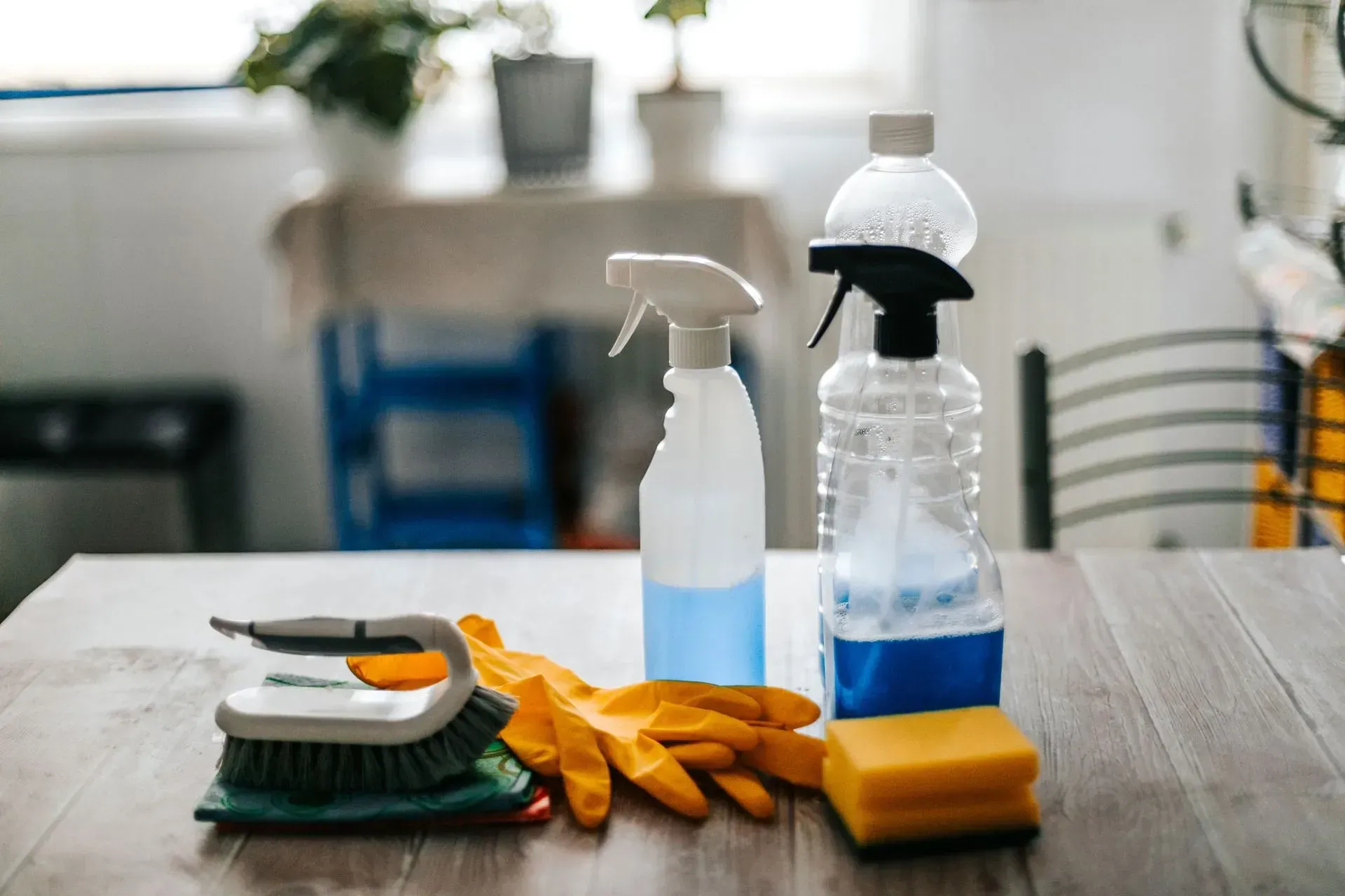 A table topped with cleaning supplies , gloves , sponges , and spray bottles.