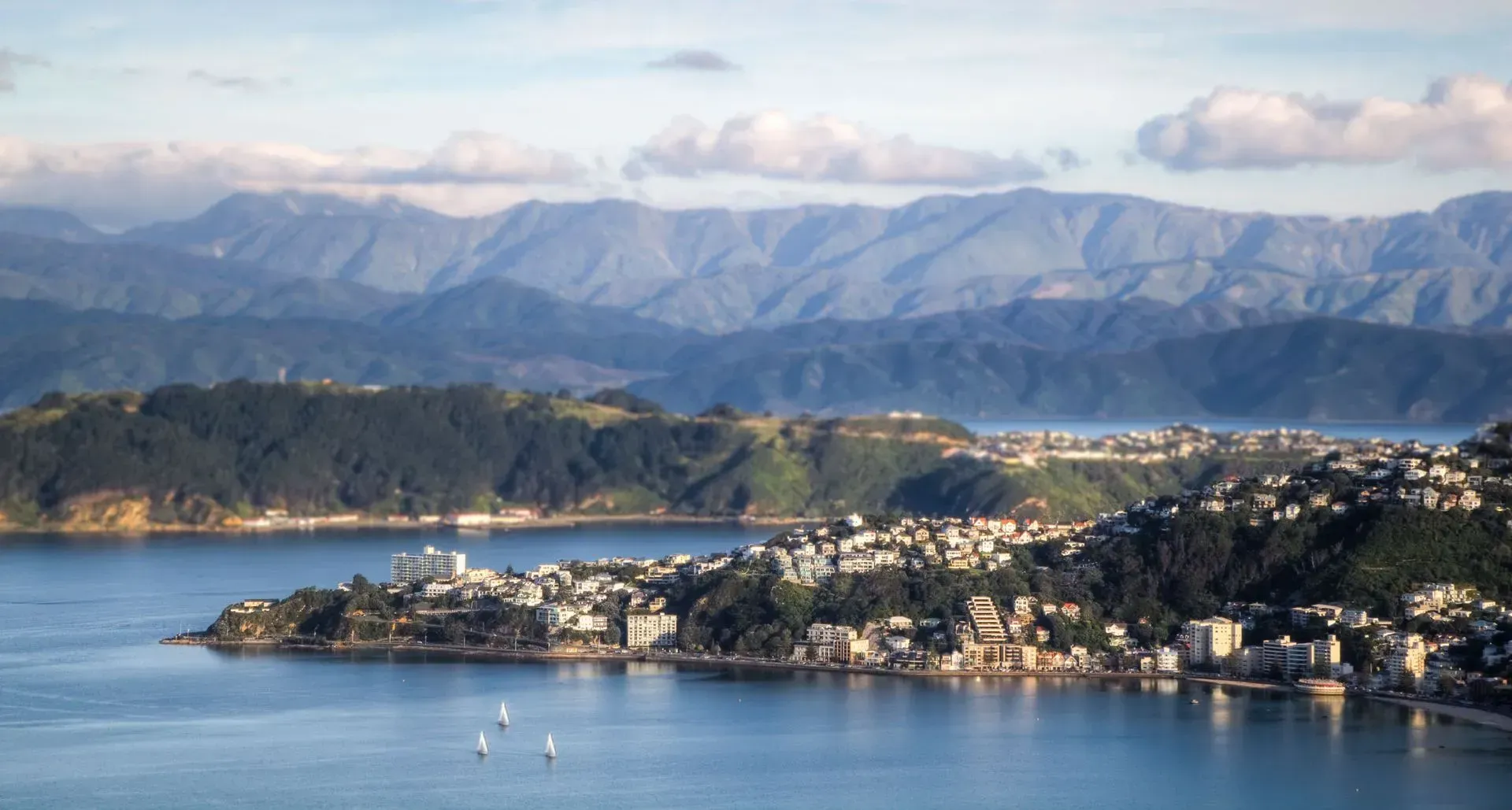 A large body of water with mountains in the background and a city in the foreground.