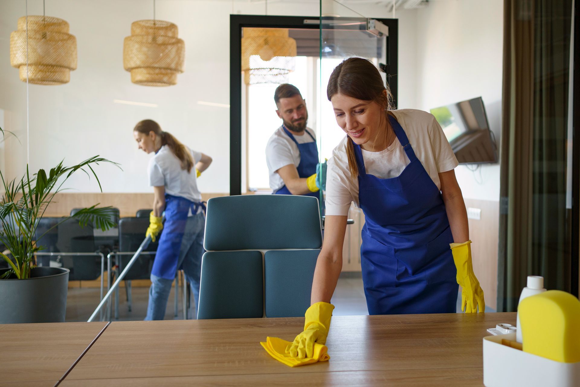 A woman is cleaning a table with a cloth in an office.