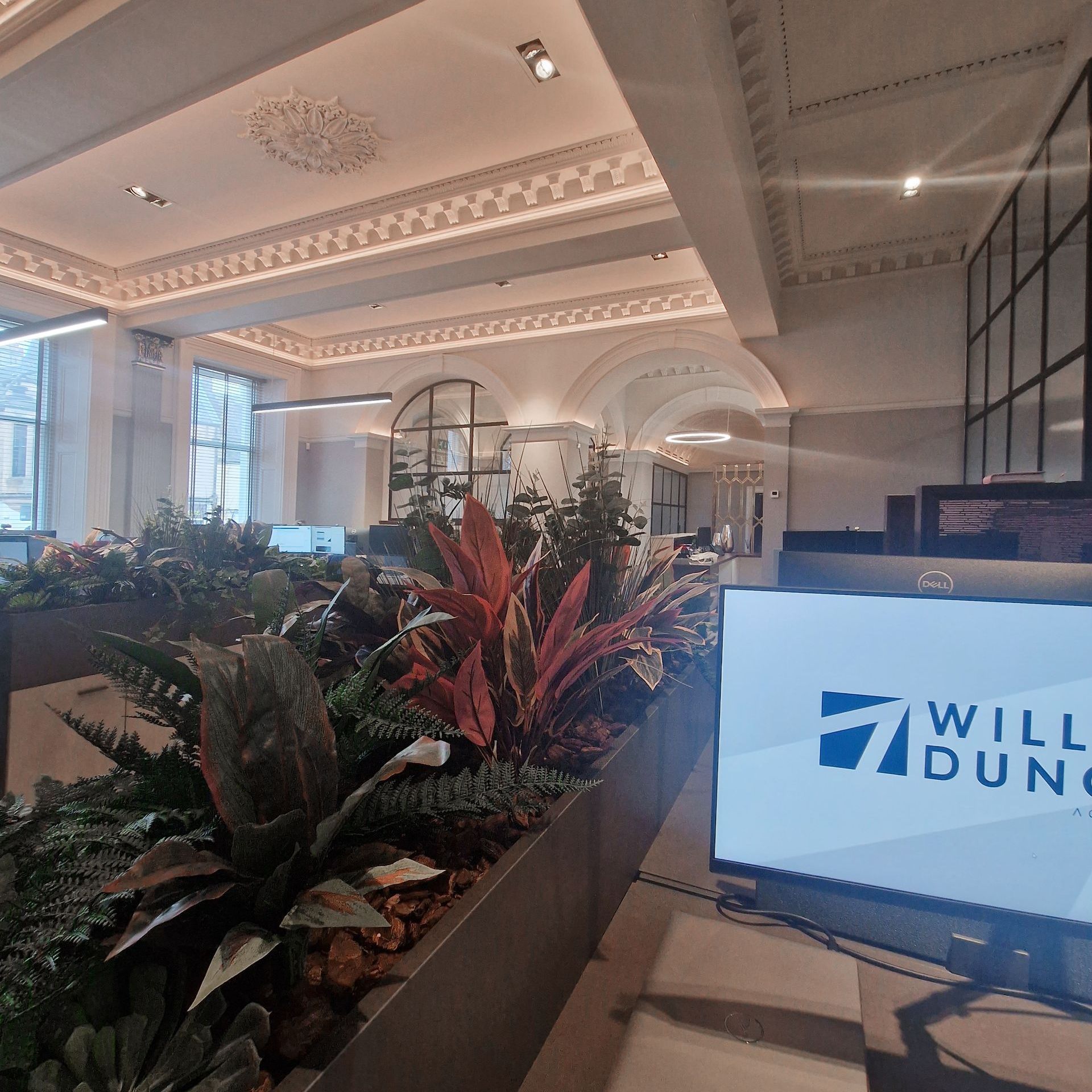 View of the William Duncan offices with lots of greenery. In the foreground is a computer screen with the William Duncan logo on it.