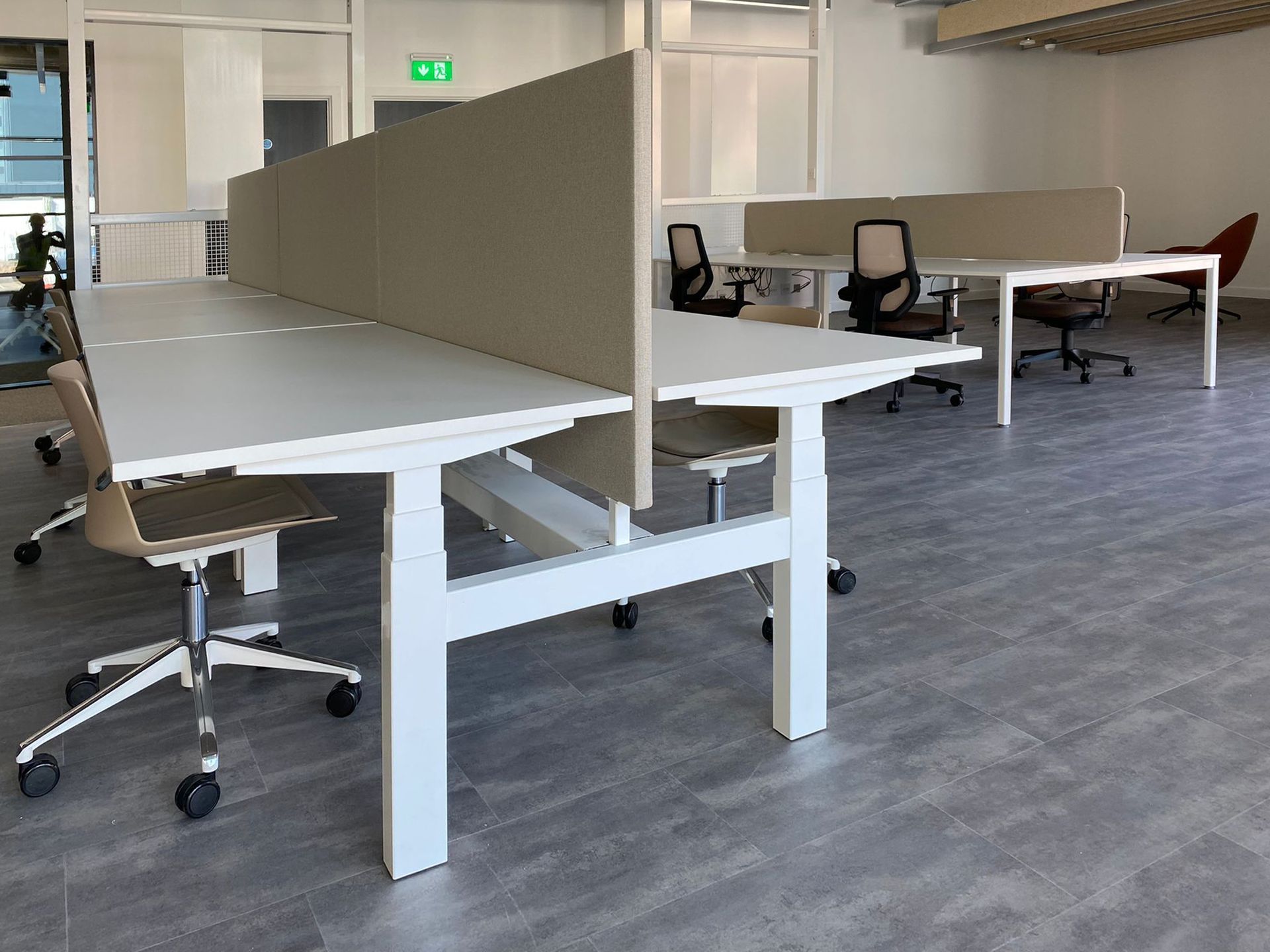 Bench desking with dividers; there is an office chair at each section.