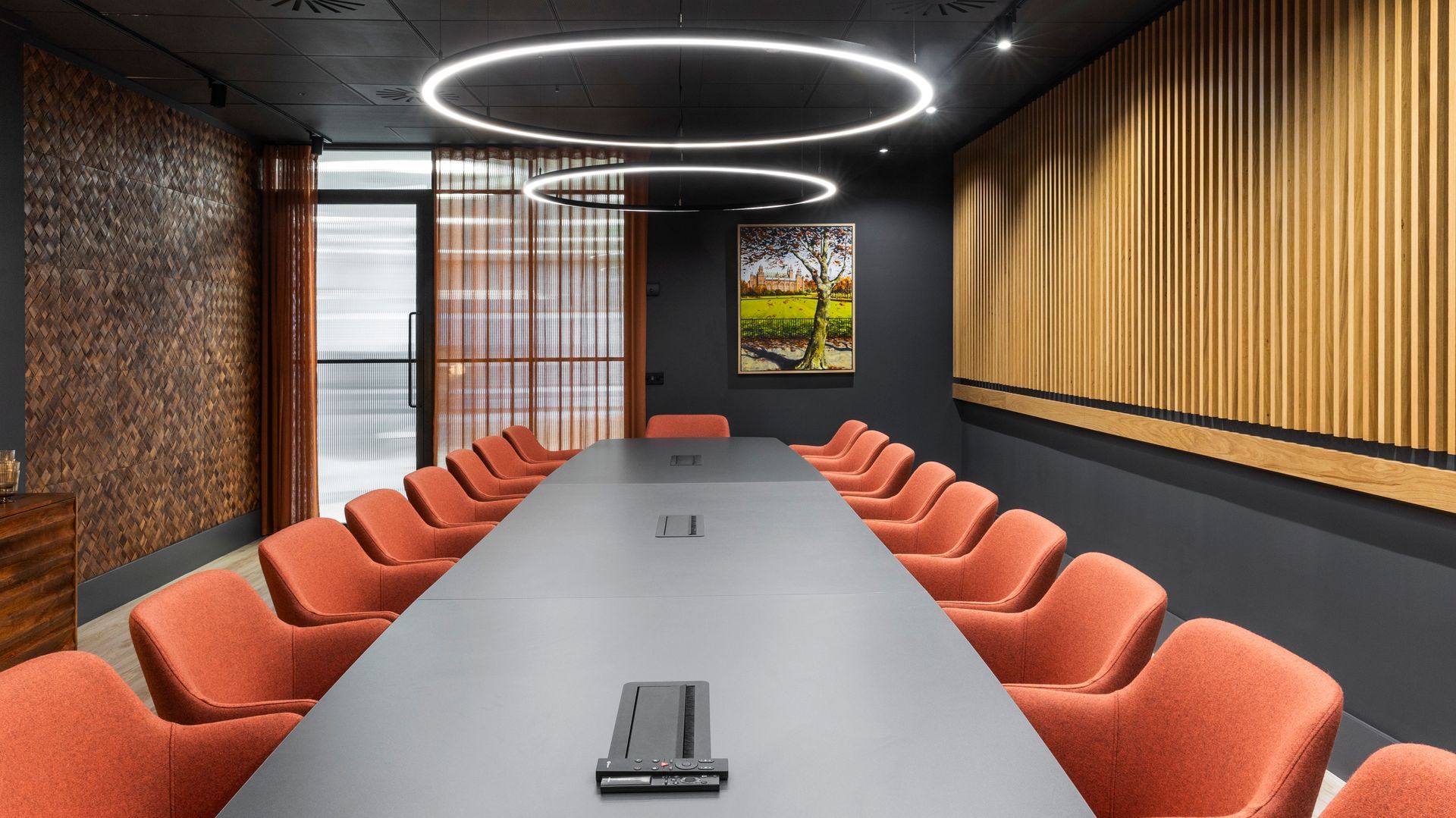 an innovative boardroom with a large board table, soft seating, and sustainably manufactured wall coverings made from banana tree bark.