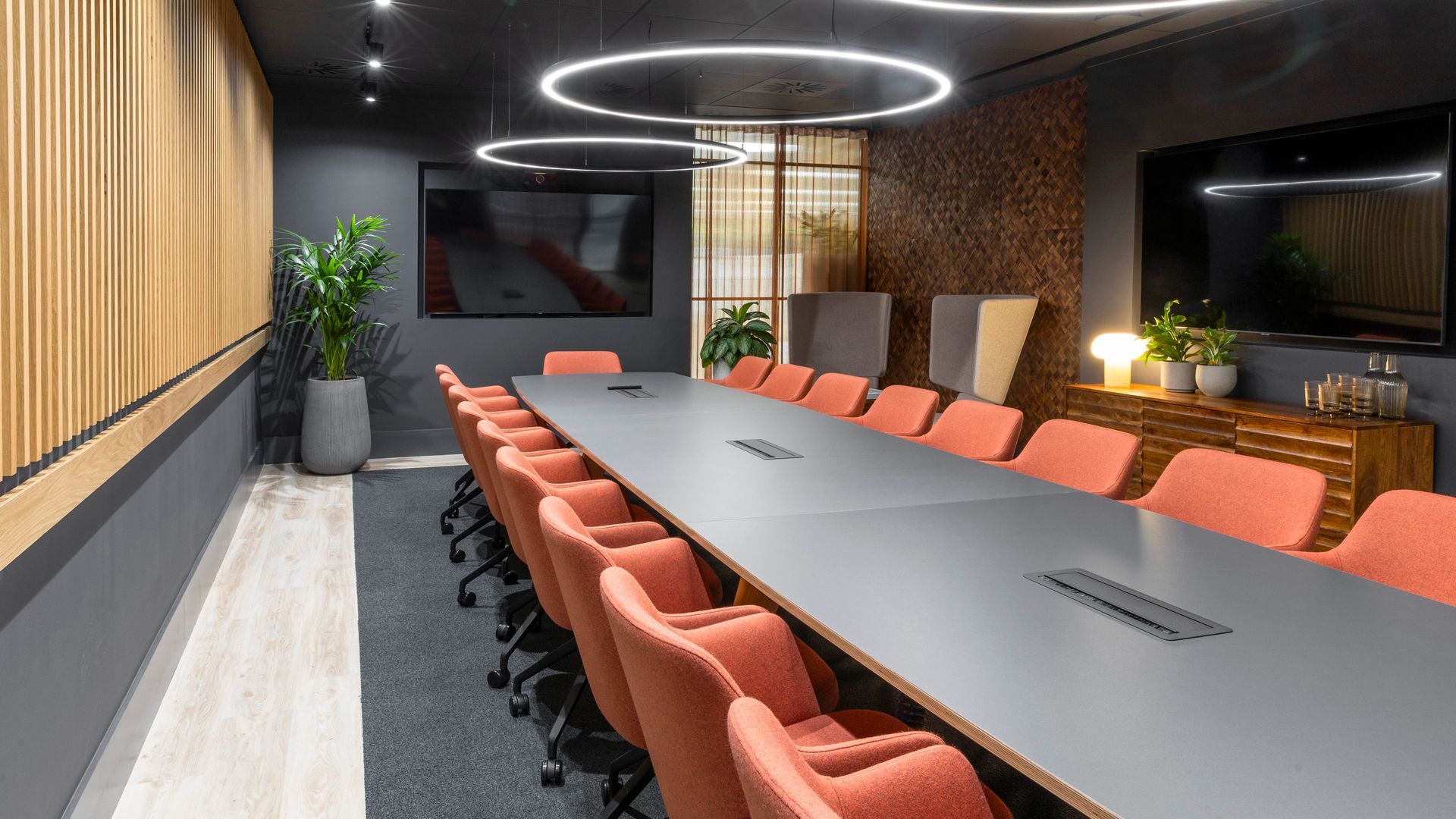 an innovative boardroom with a large board table, soft seating, and sustainably manufactured wall coverings made from banana tree bark.