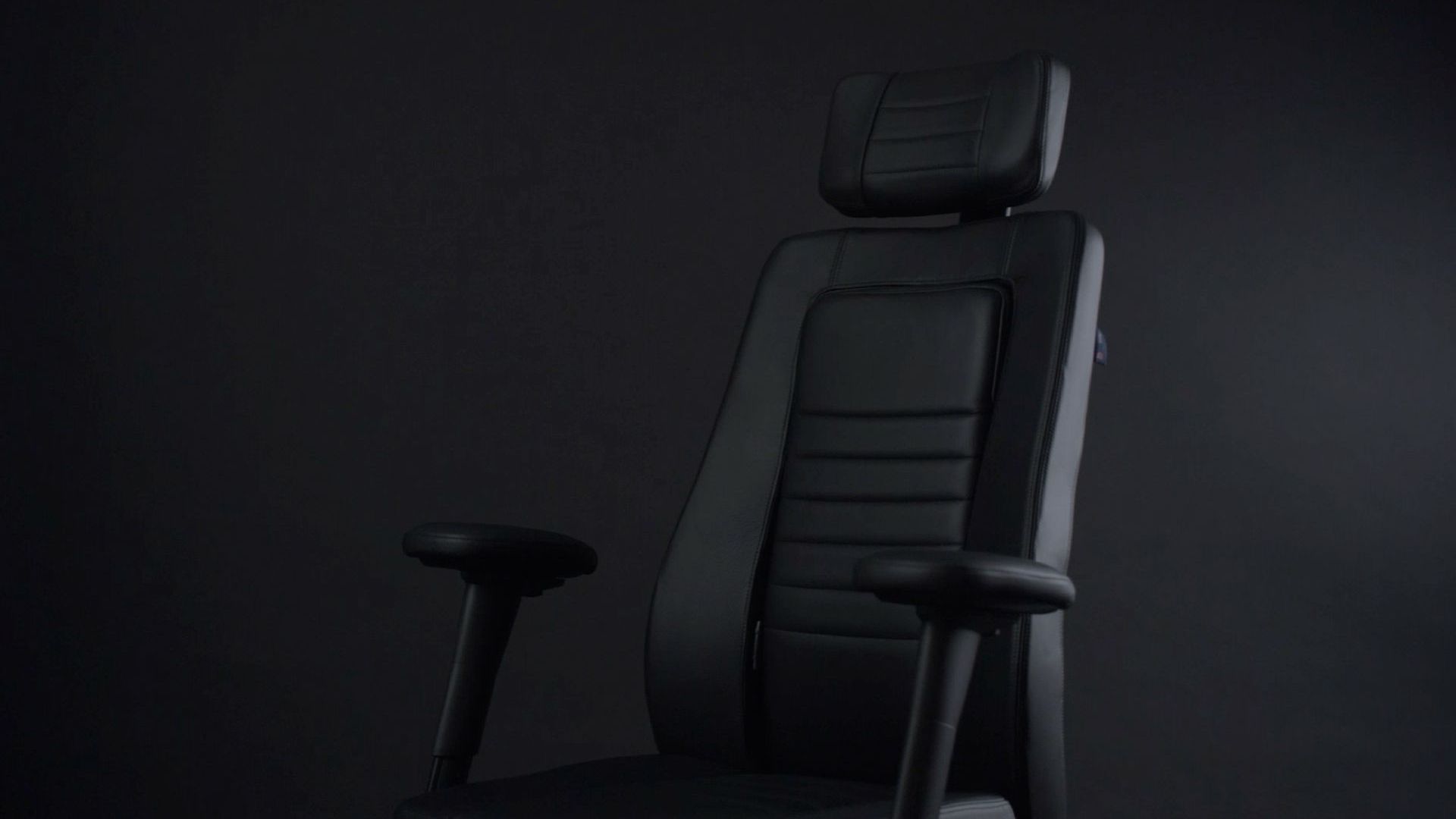 close up of the top half of the flokk rh focus chair in black in front of a black wall