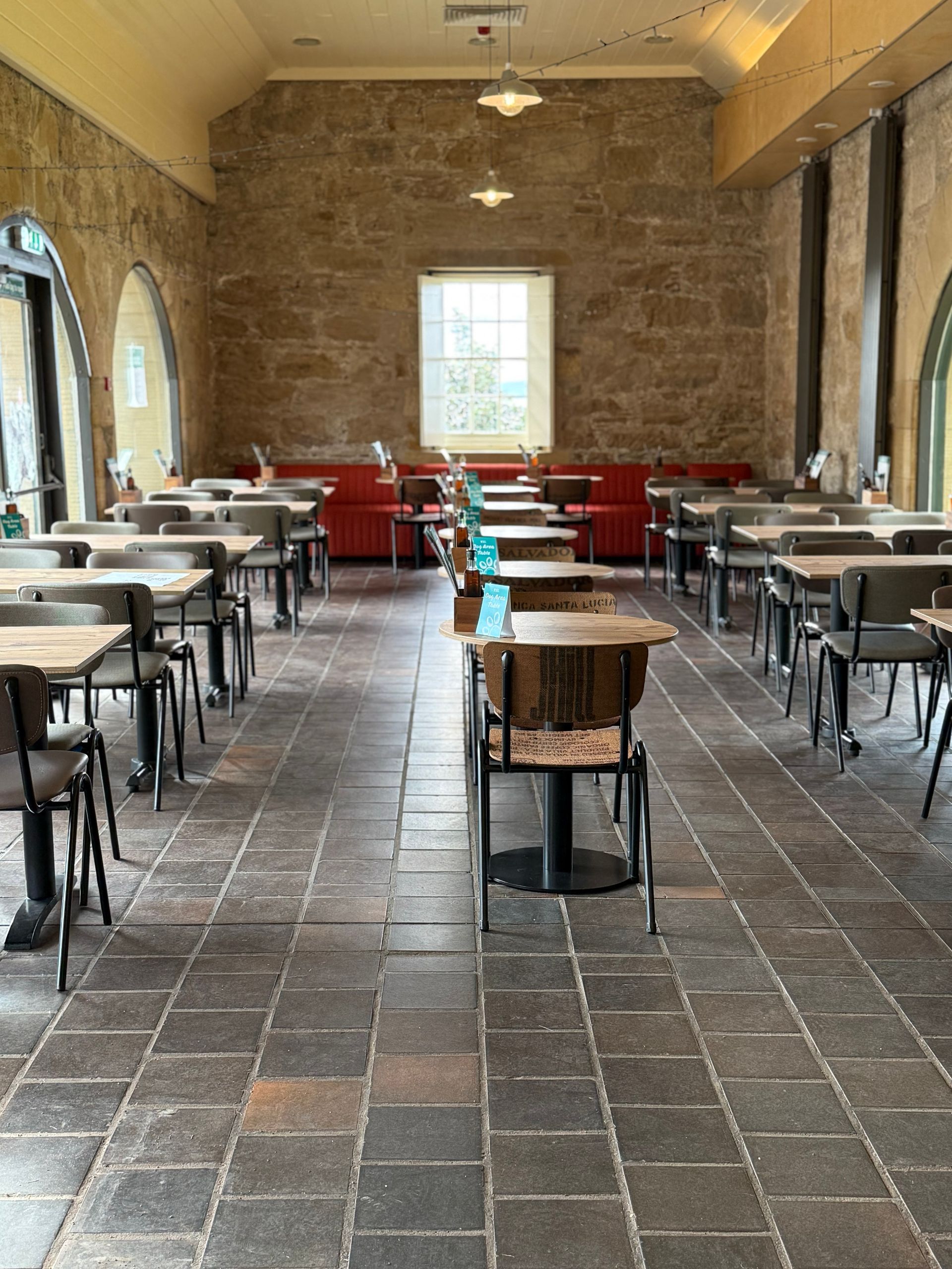 Culzean Castle cafeteria interior with tables, chairs, stone walls, and a red booth.