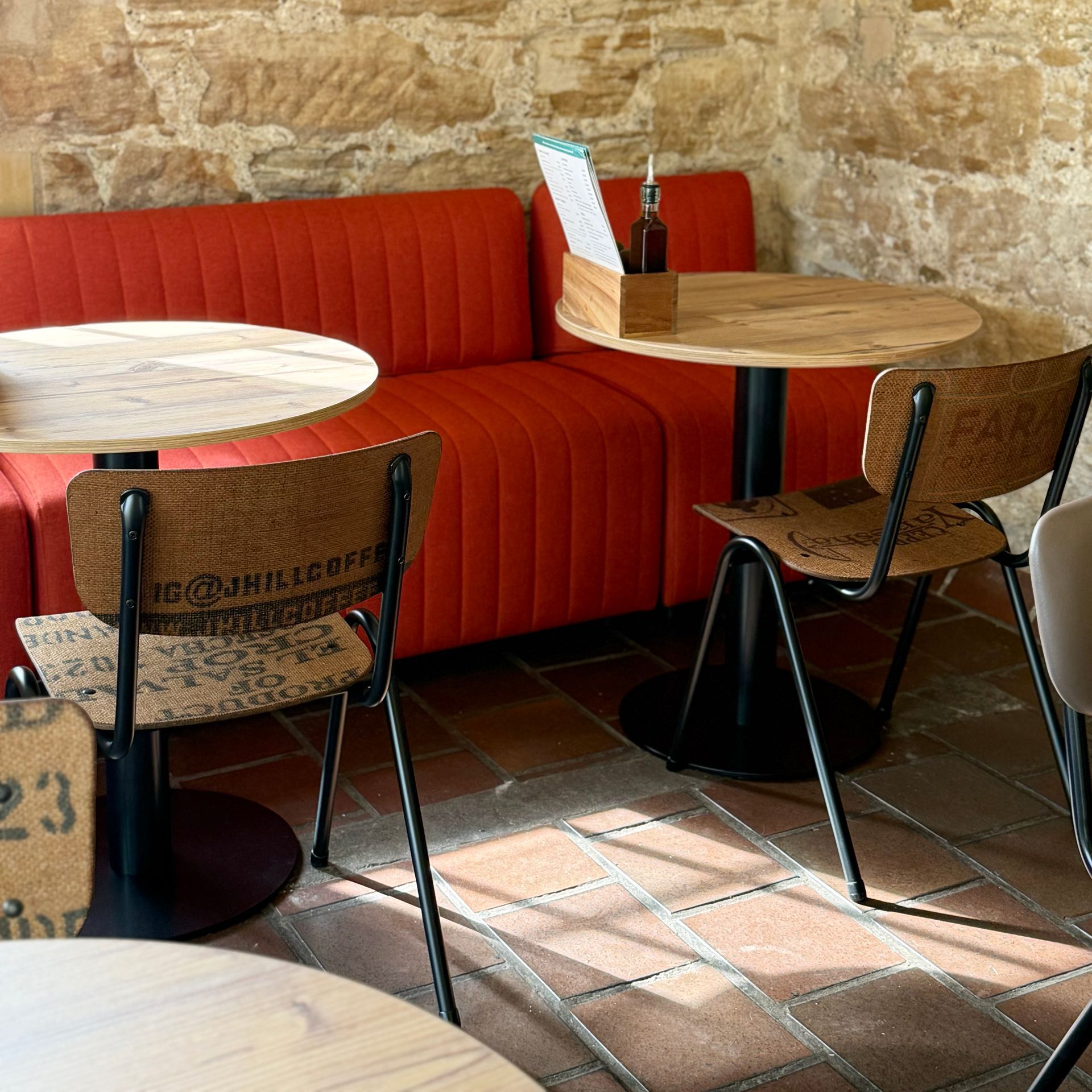 Culzean Castle cafe interior with red booth seating, round wooden tables, and chairs with coffee bag backs.