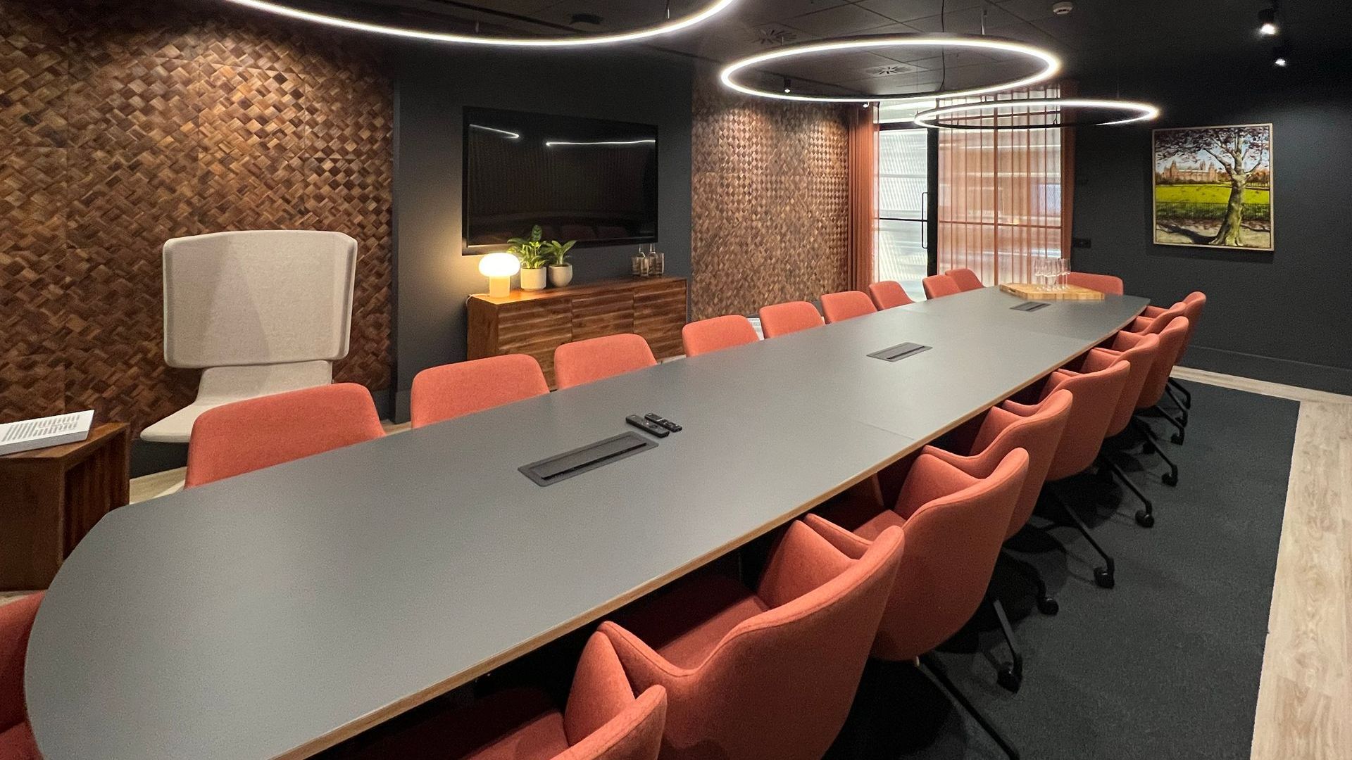 an innovative boardroom with a large board table, soft seating, and sustainably manufactured wall coverings made from banana tree bark.