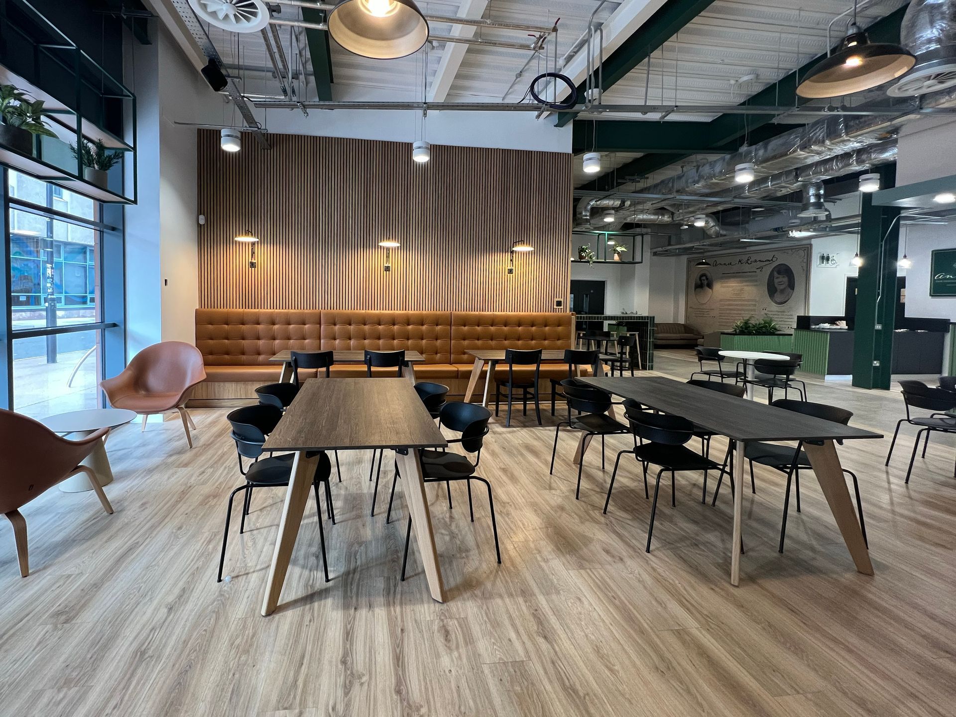 Another angle of the larger tables available in Annie's Cafe, including light oak tables and dark wood. At each table is a mix of dining chairs, armchairs, and bench seating.
