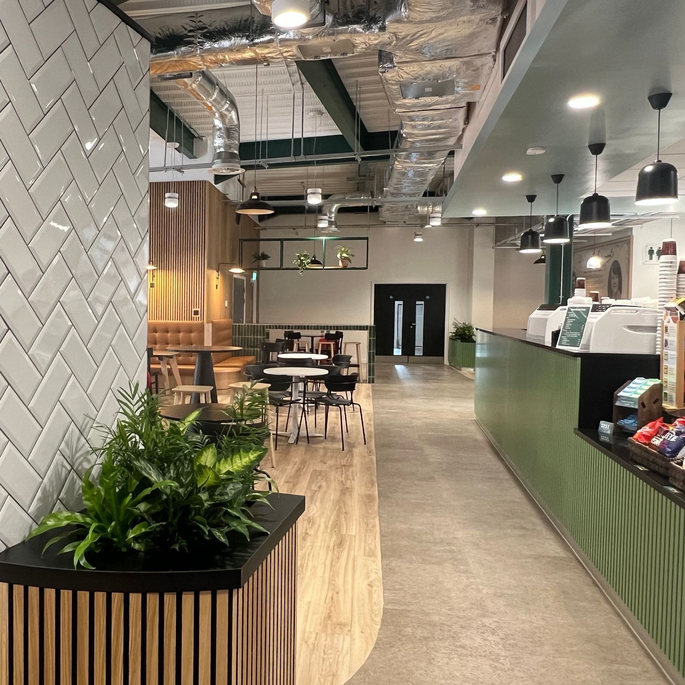 View of the counter where people can order food. It has green panelling and black countertops.