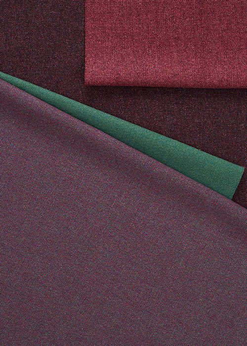 Close-up of folded fabrics in various colors: burgundy, deep red, emerald green, and purple.