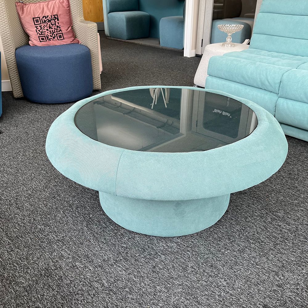 Light blue corduroy coffee table with a round glass top.