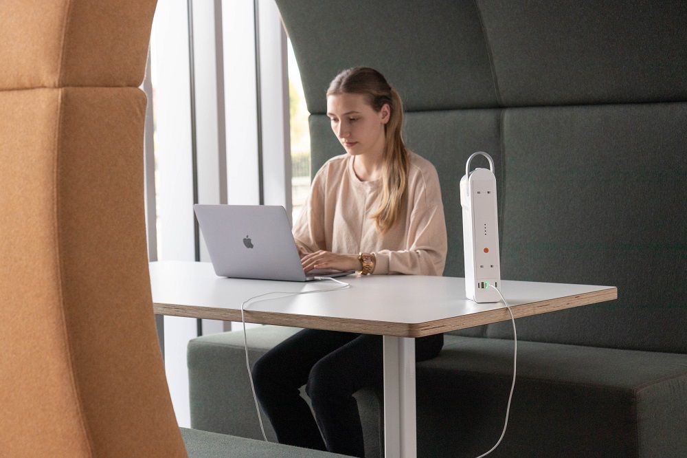 A woman at a desk using the QikPac Carry unit and utilising power from anywhere in the office