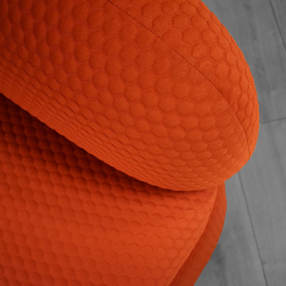 Orange upholstered chair with textured, bubble-like pattern, close-up detail.