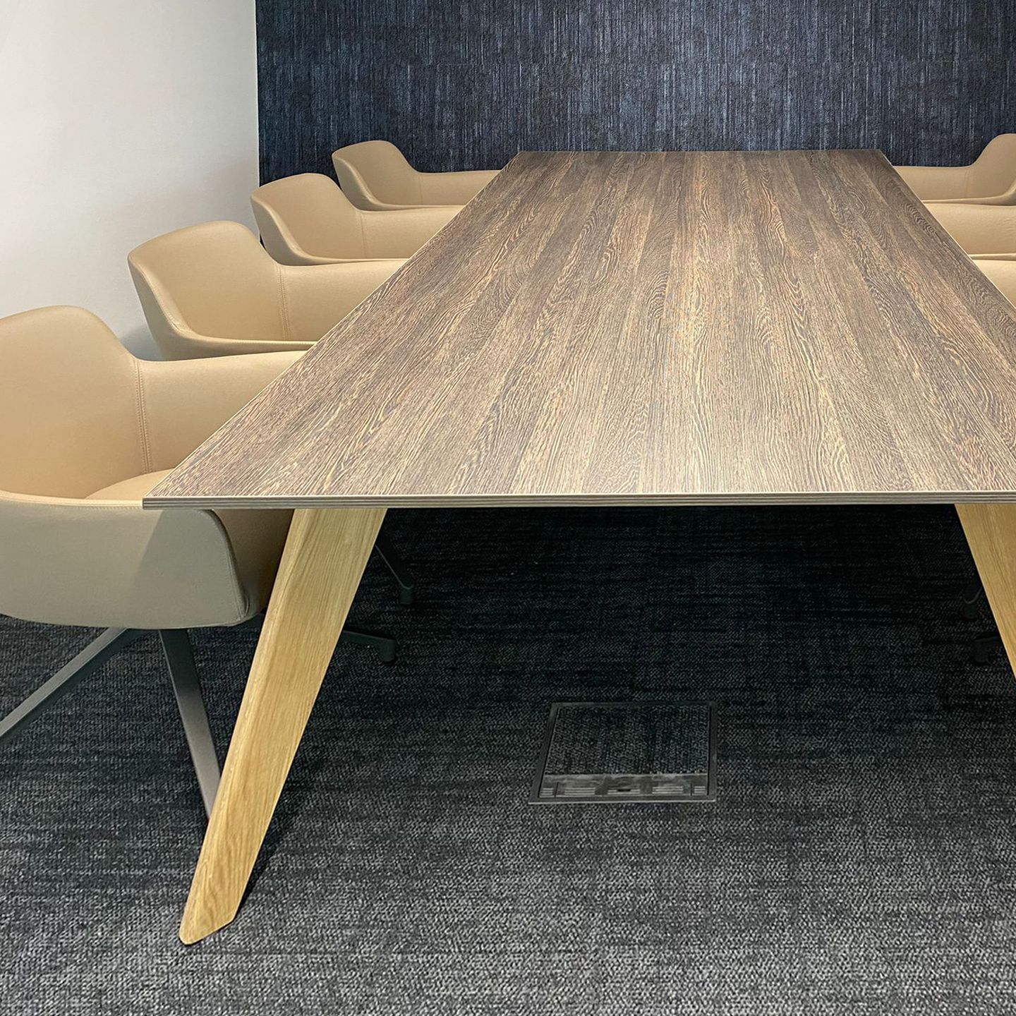 Wooden conference table with eight chairs, four on either side.