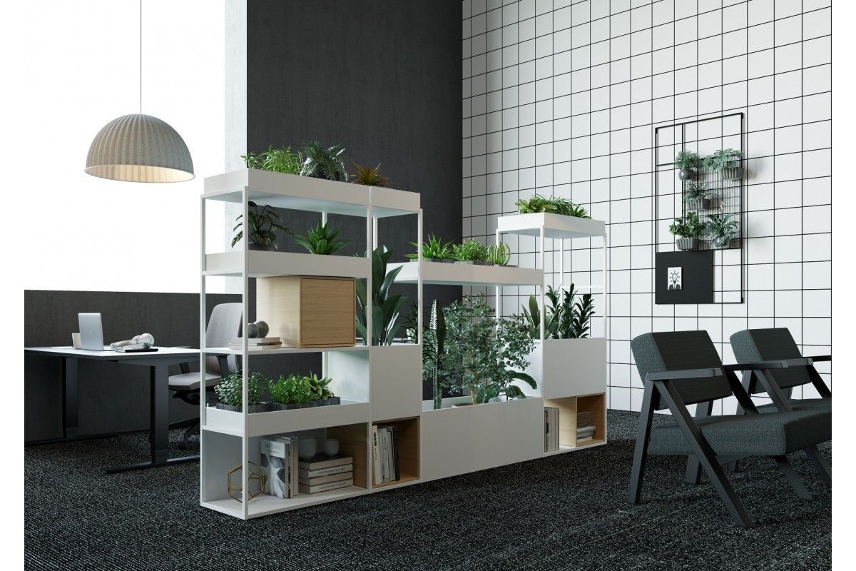 White office divider with plants, shelves, and a work area with a gray carpet floor.