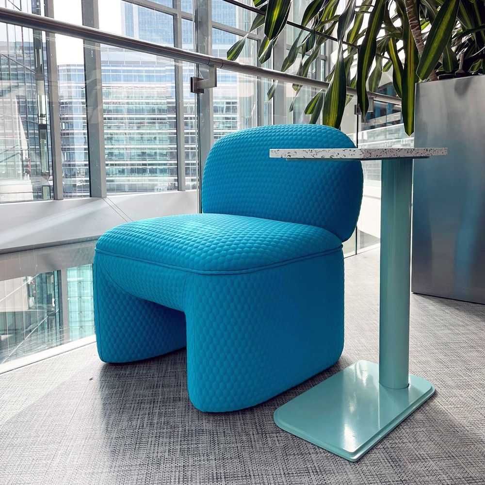 Blue upholstered chair and side table by a window.