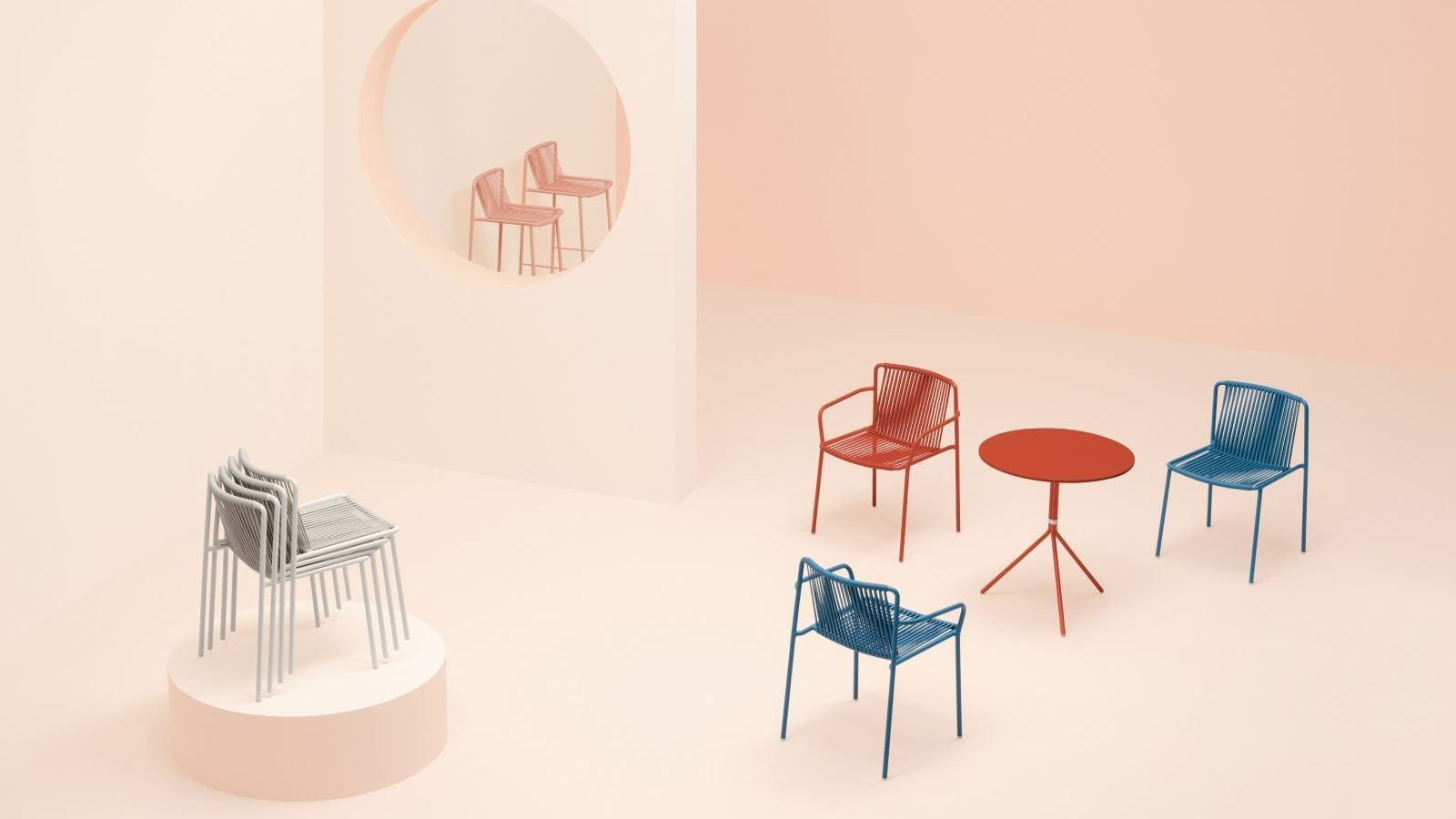 Pedrali furniture dotted around a large spacious room in a modern layout. The chairs are red, peach and blue. A stack of grey Tribeca 3660 chairs are on top of a pedestal. 