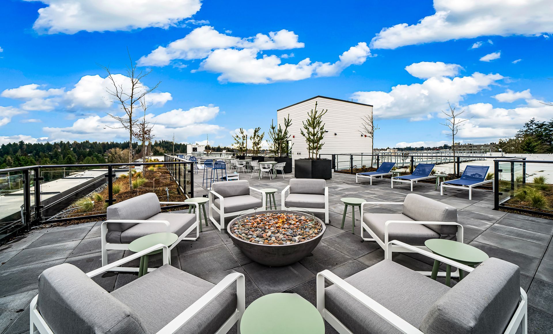 There is a fire pit on the roof of a building surrounded by chairs and tables.