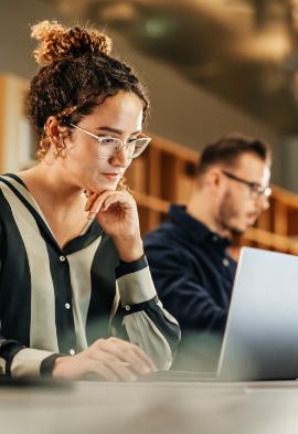 A woman is sitting at a table using a laptop computer.